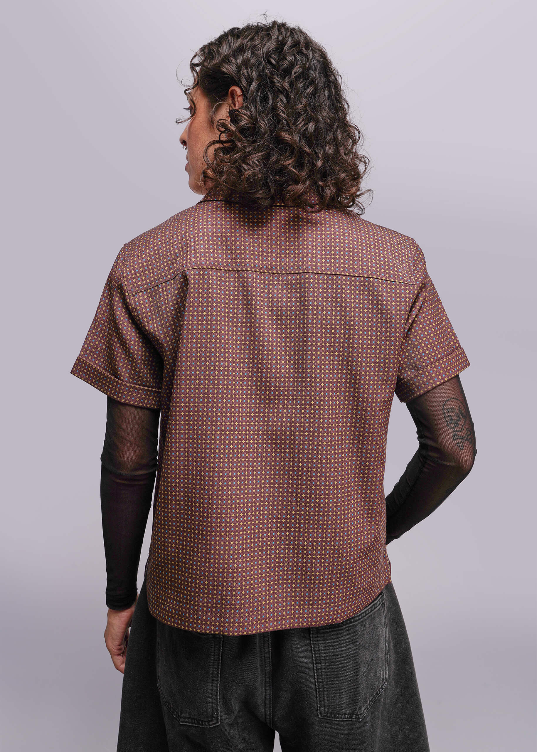 S=Person wearing a brown patterned shirt from behind on a light gray background