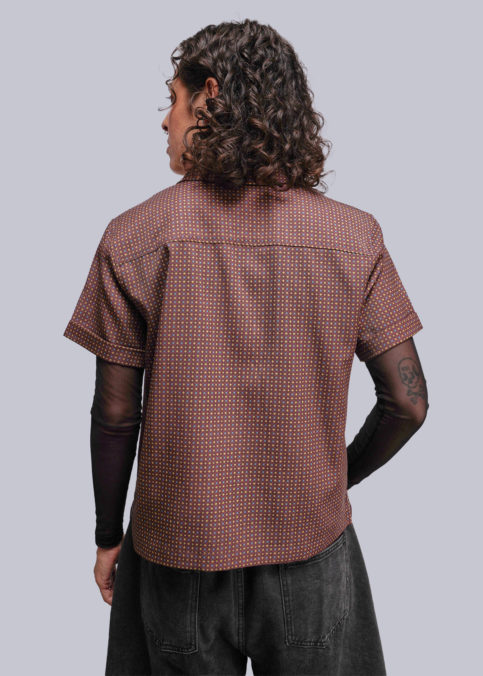 S=Person wearing a brown patterned shirt from behind on a light gray background