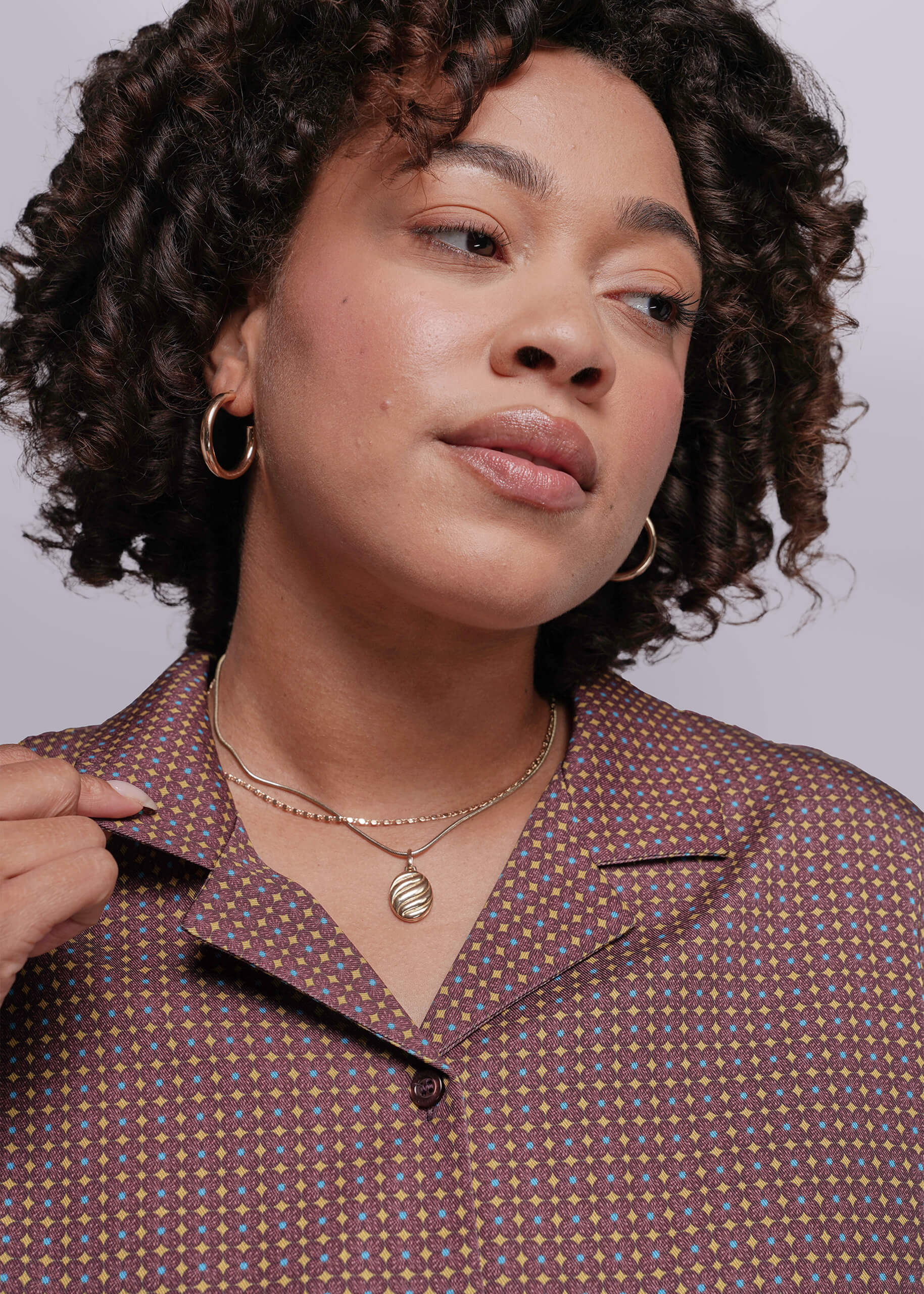 1X=Woman wearing a patterned shirt with a neutral background