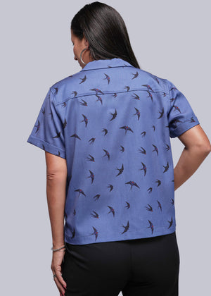 S=Back of person wearing a blue shirt with bird pattern on a plain background