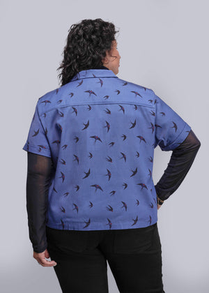 1X=Person wearing a blue jacket with bird pattern on a plain background