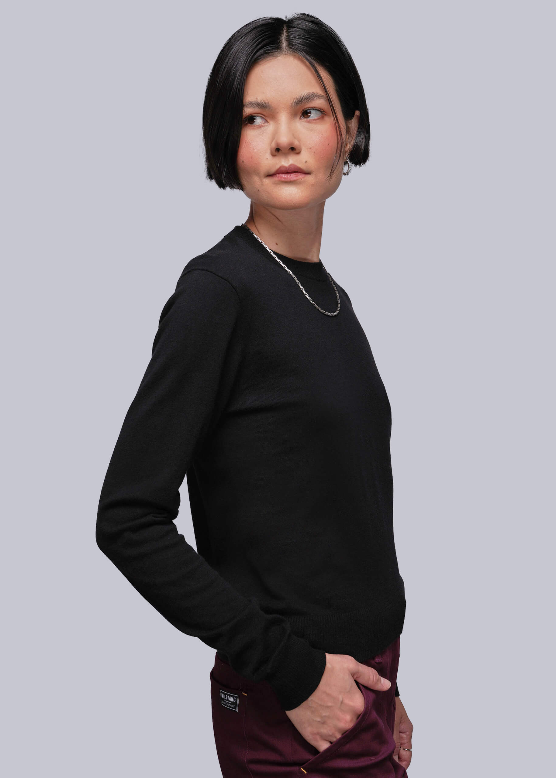 S=Person wearing a black long-sleeve sweater against a gray background