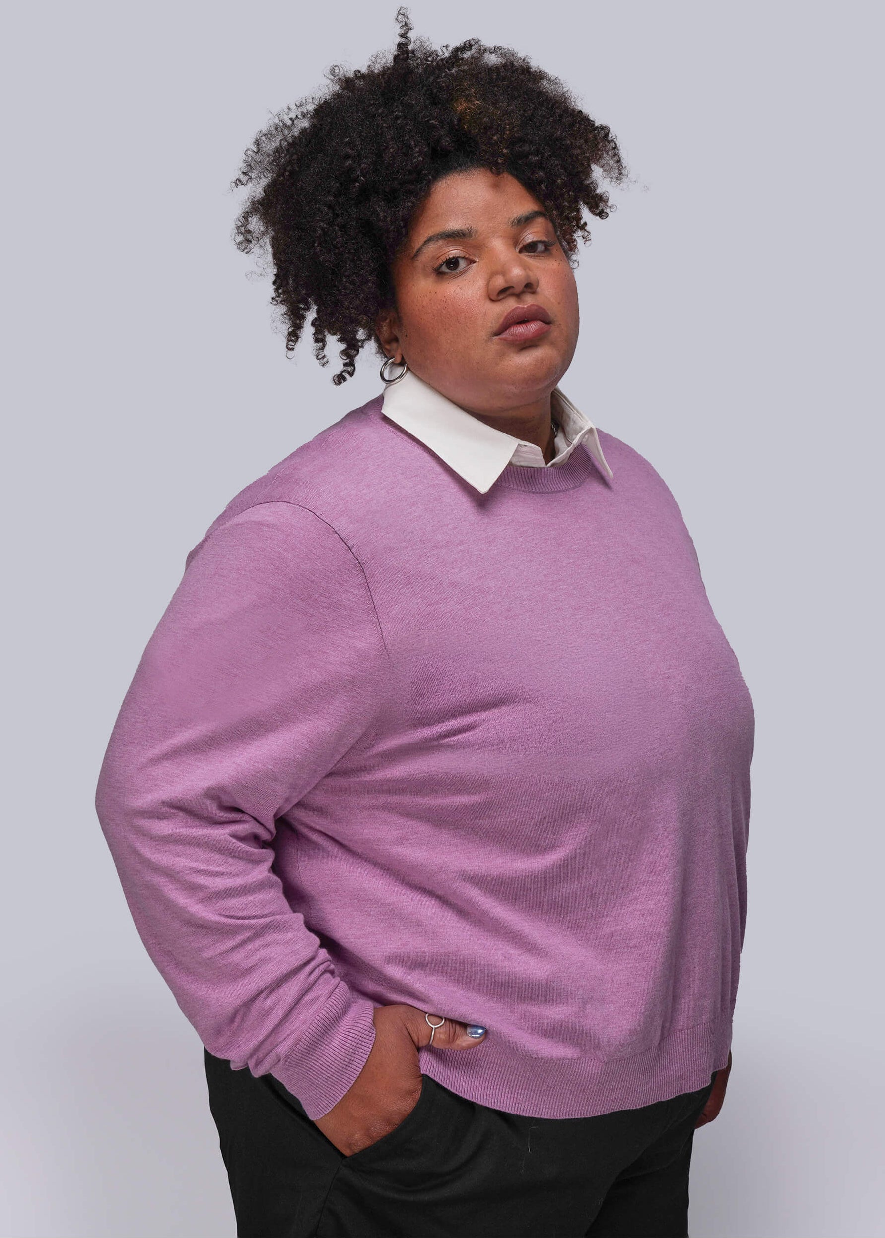 1X=Person wearing a pink sweater over a white shirt on a plain background