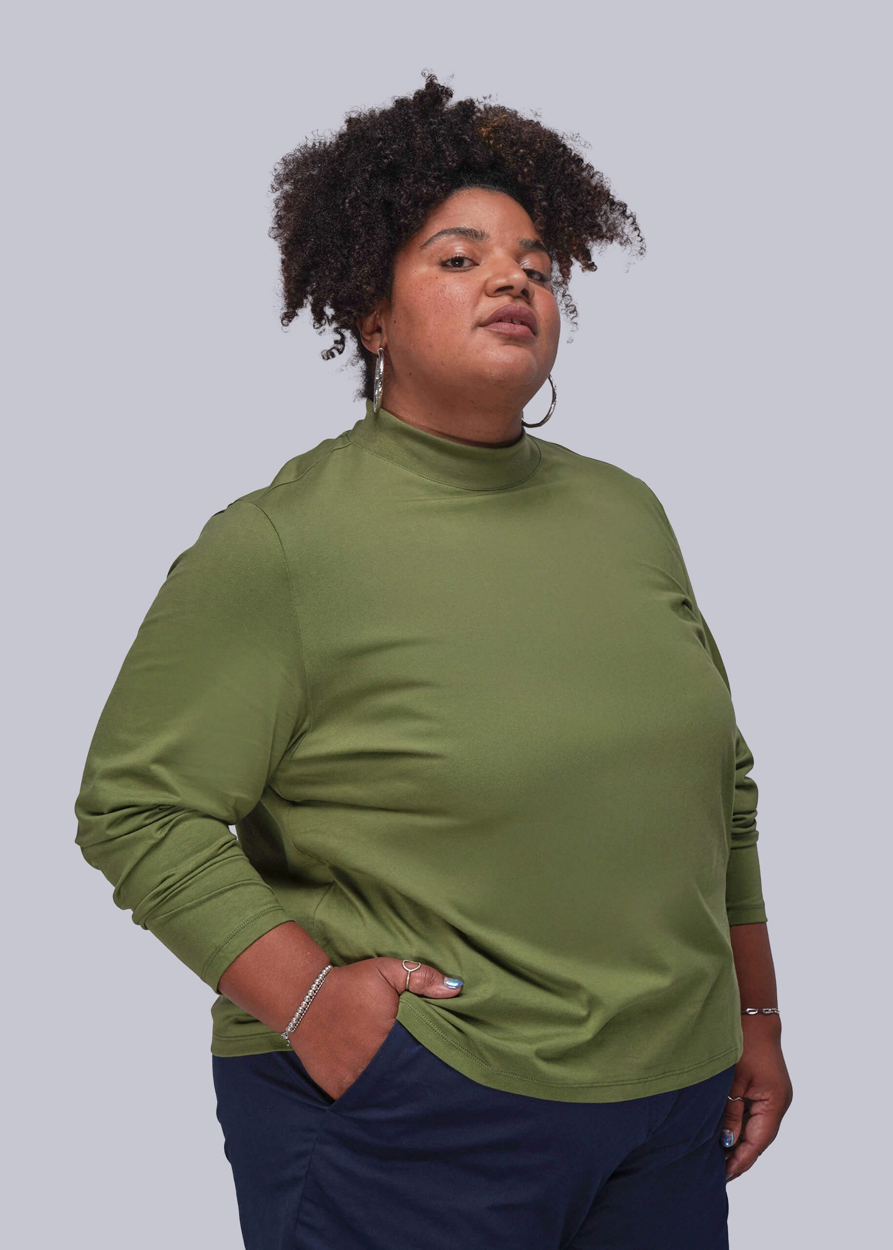 1X=Person wearing a green long-sleeve top against a plain background
