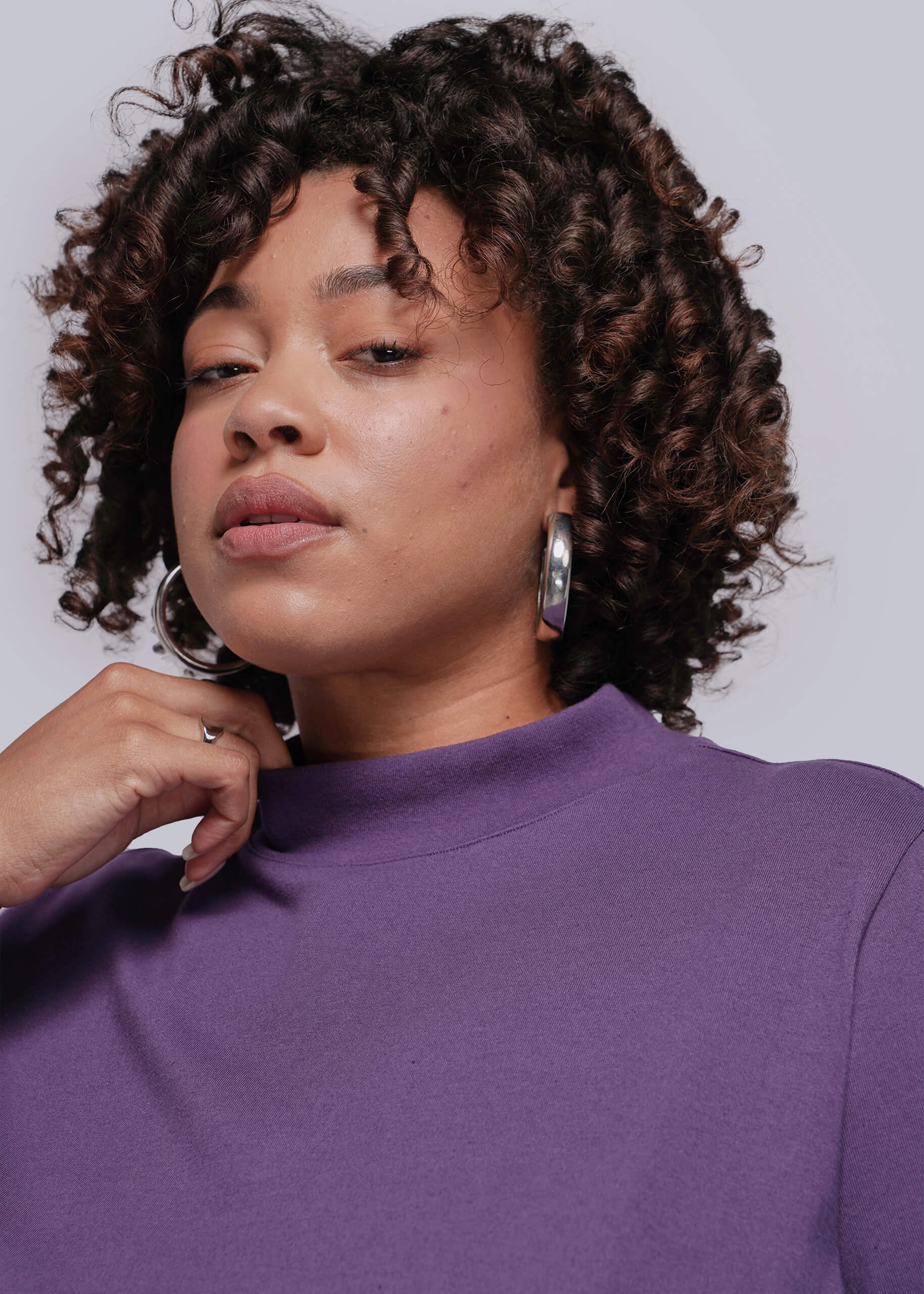 1X=Woman wearing a purple top with a plain background