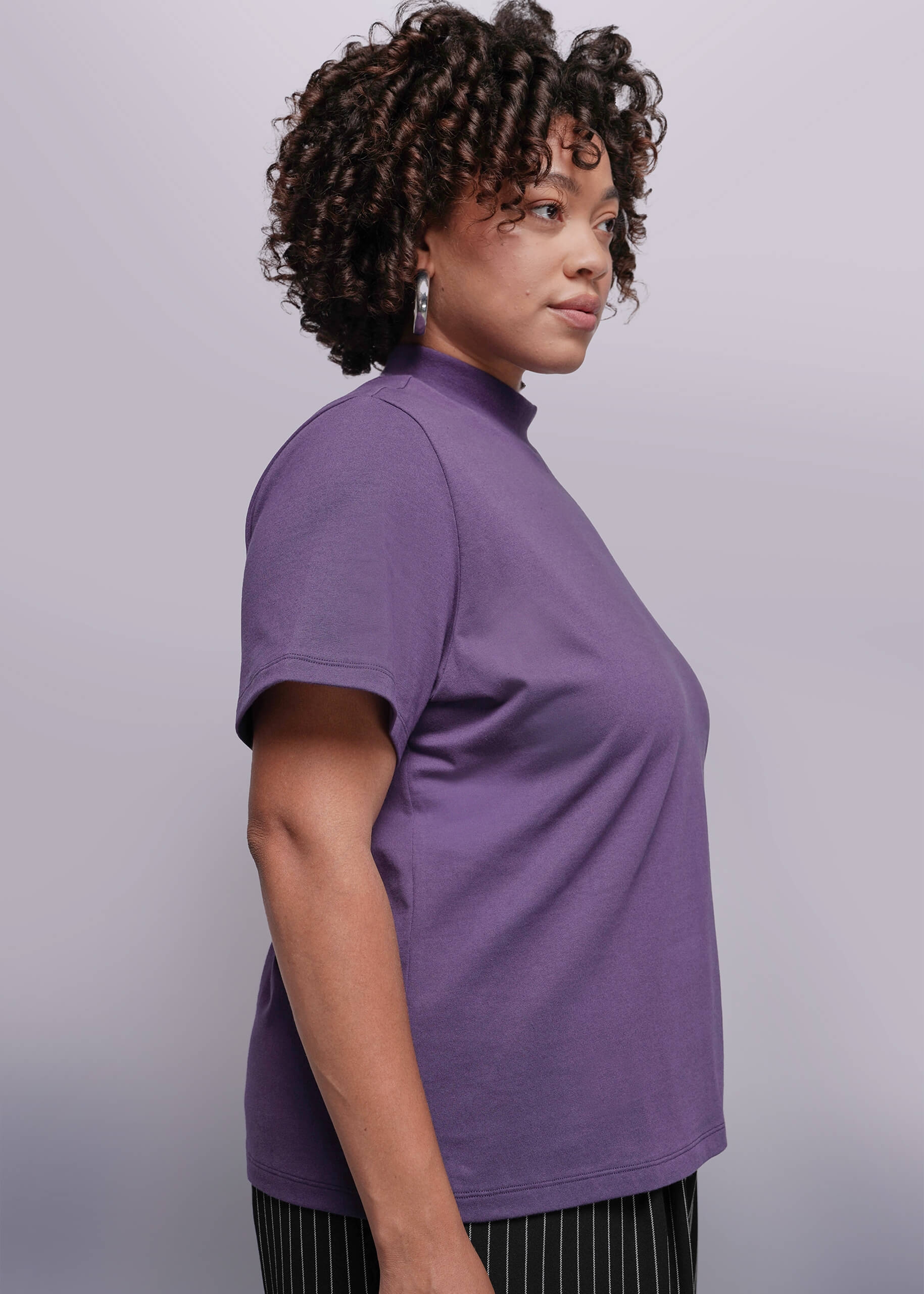 1X=Woman wearing a purple t-shirt against a plain background