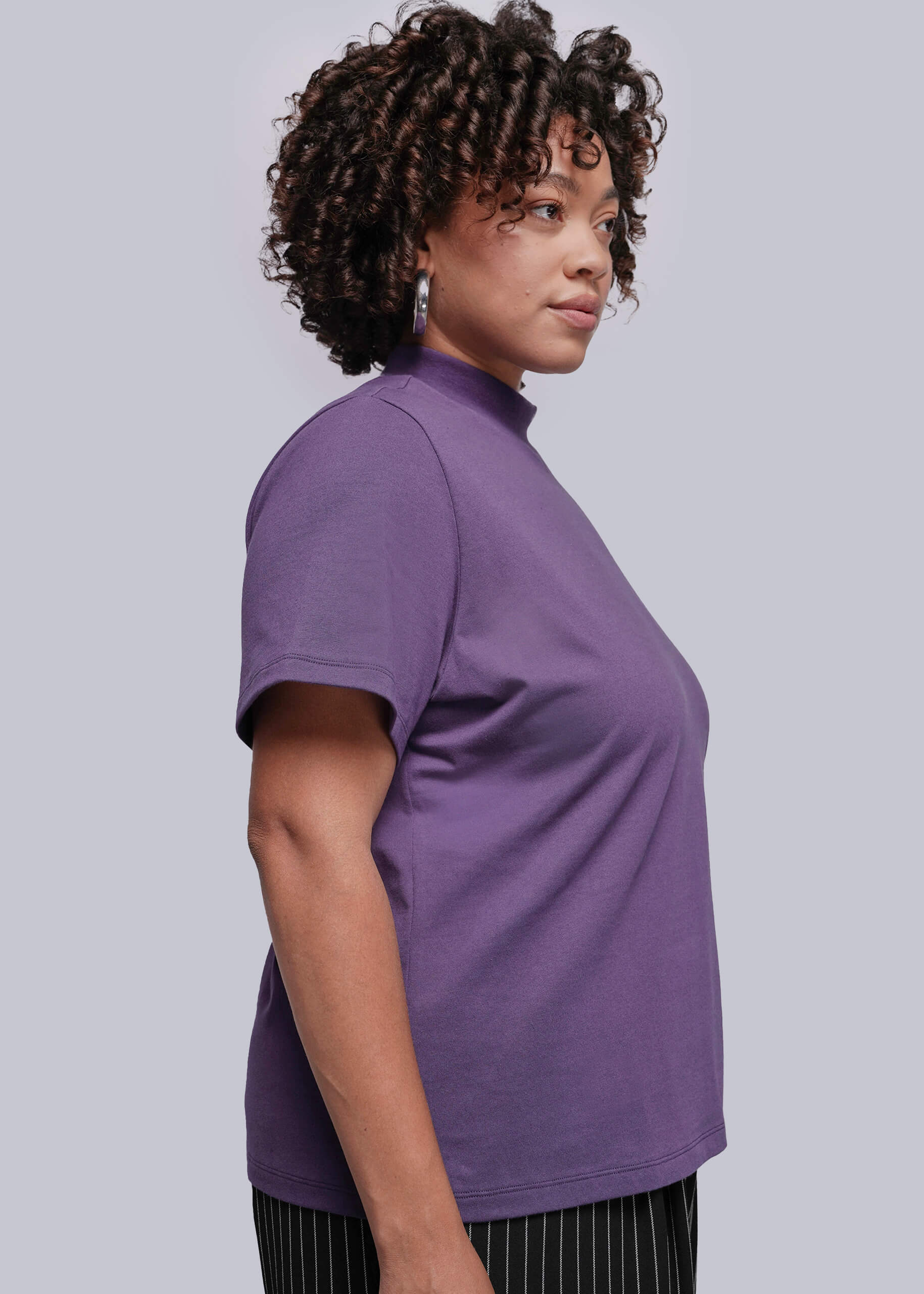 1X=Woman wearing a purple t-shirt against a plain background