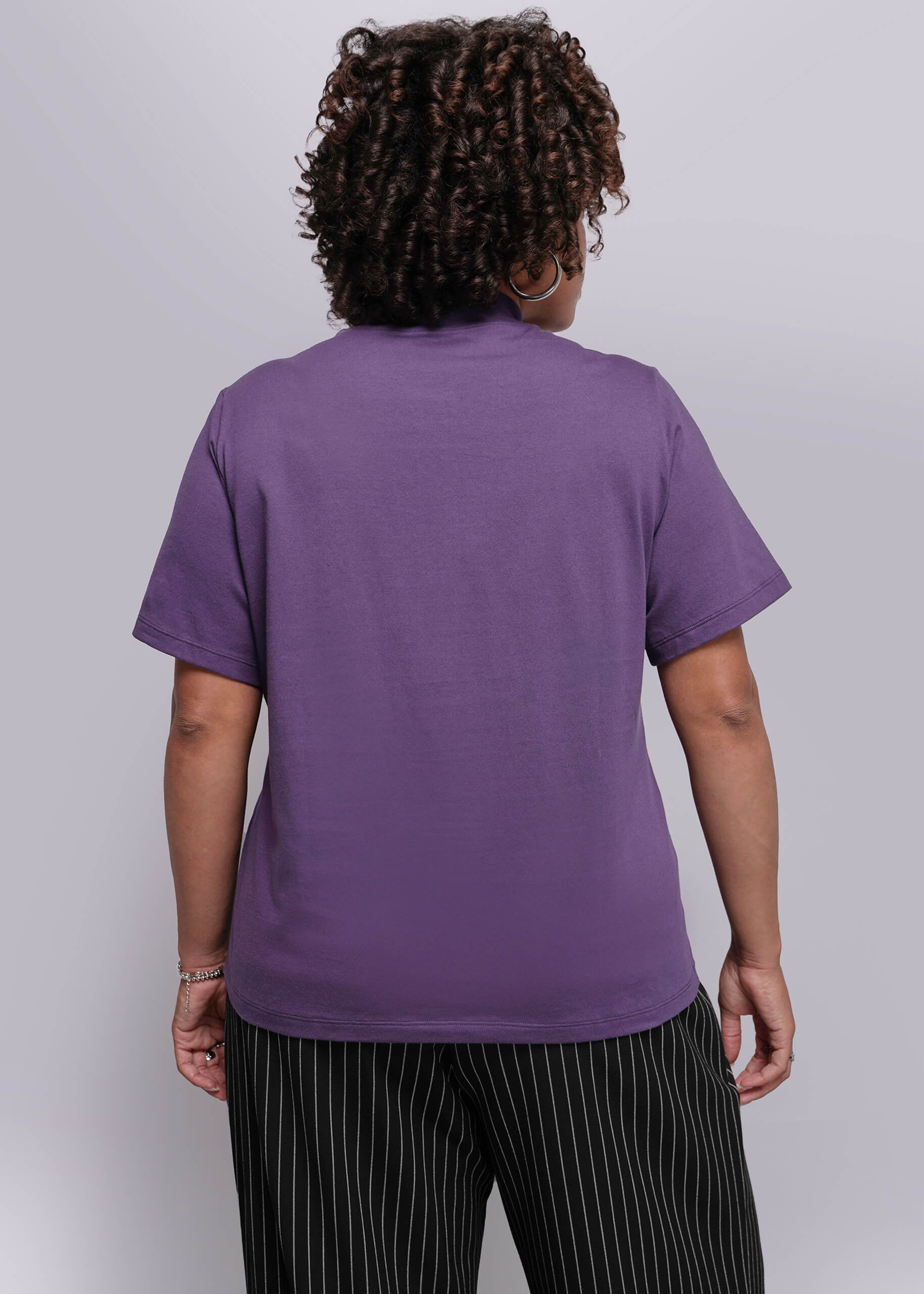 1X=Person wearing a purple t-shirt and black striped pants against a white background