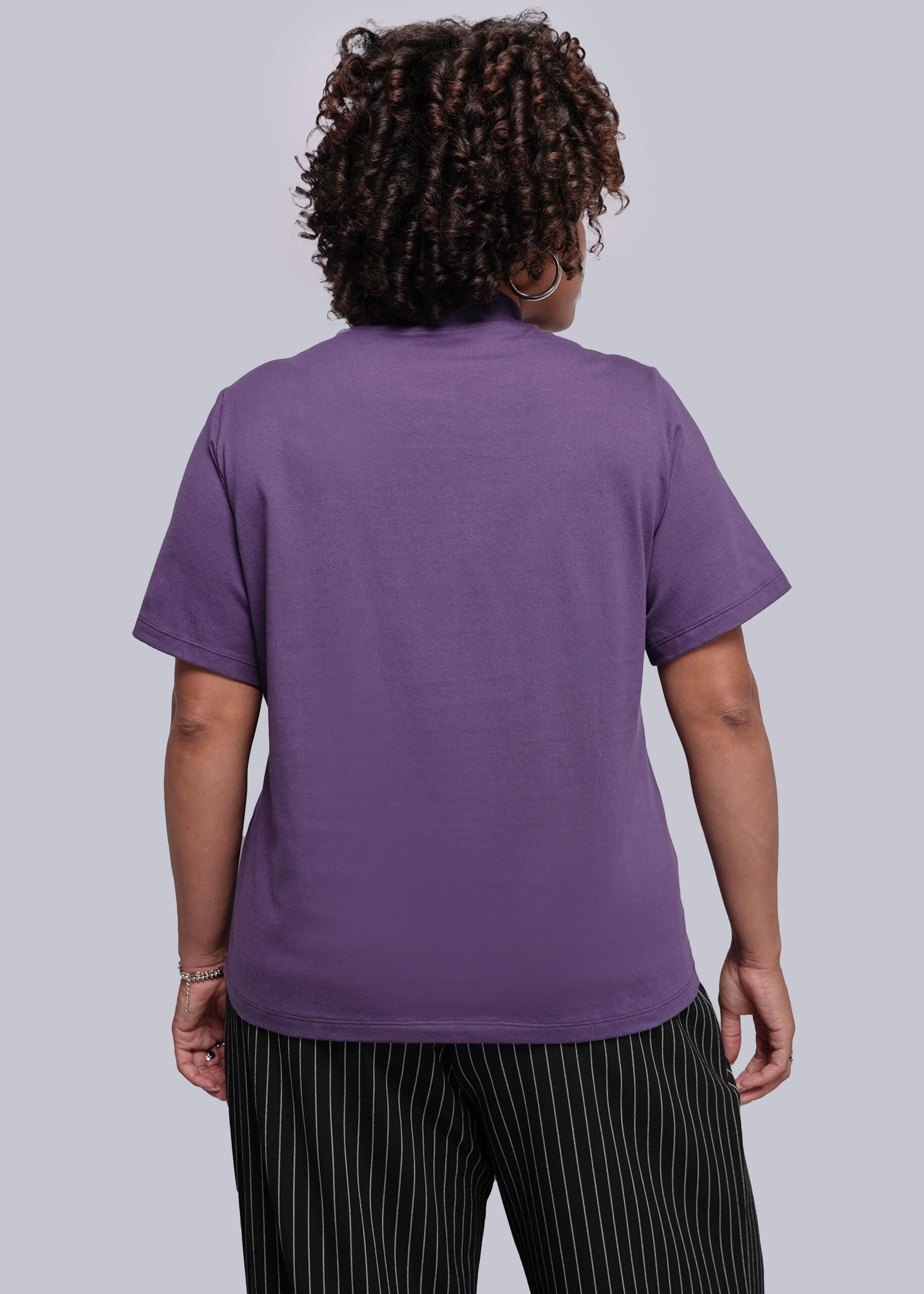 1X=Person wearing a purple t-shirt and black striped pants against a white background