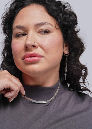 1X=Woman wearing a silver necklace against a neutral background