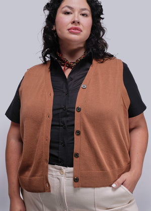 1X=Person wearing a brown vest over a black shirt with a plain background
