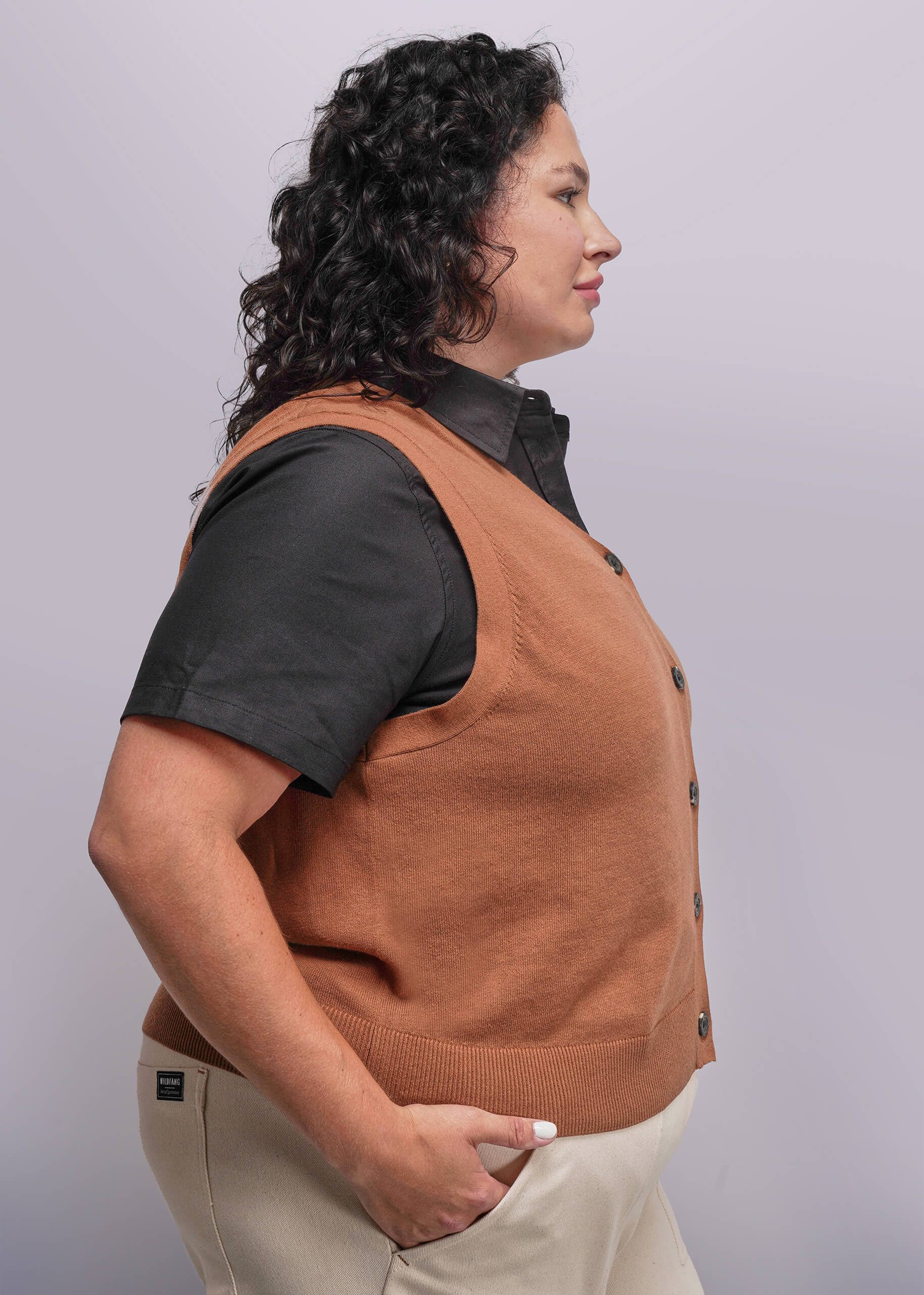 1X=Person wearing a brown vest over a black shirt on a plain background