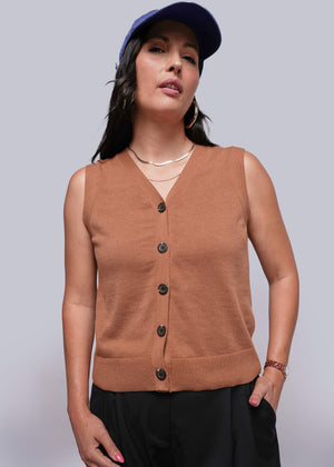 S=Woman wearing a brown sleeveless sweater vest with black buttons on a plain background