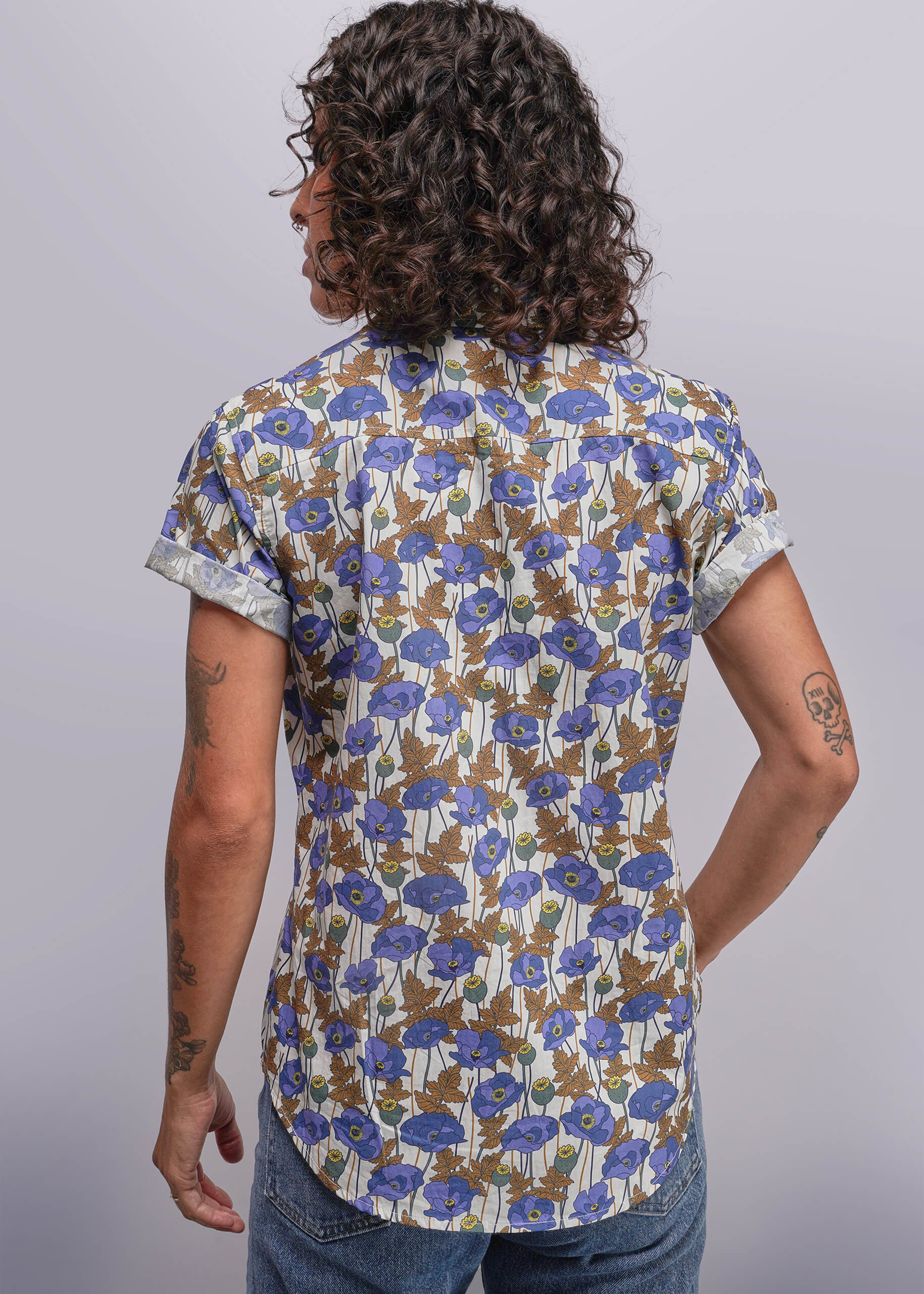 S=Person wearing a floral short-sleeve shirt with blue flowers on a plain background