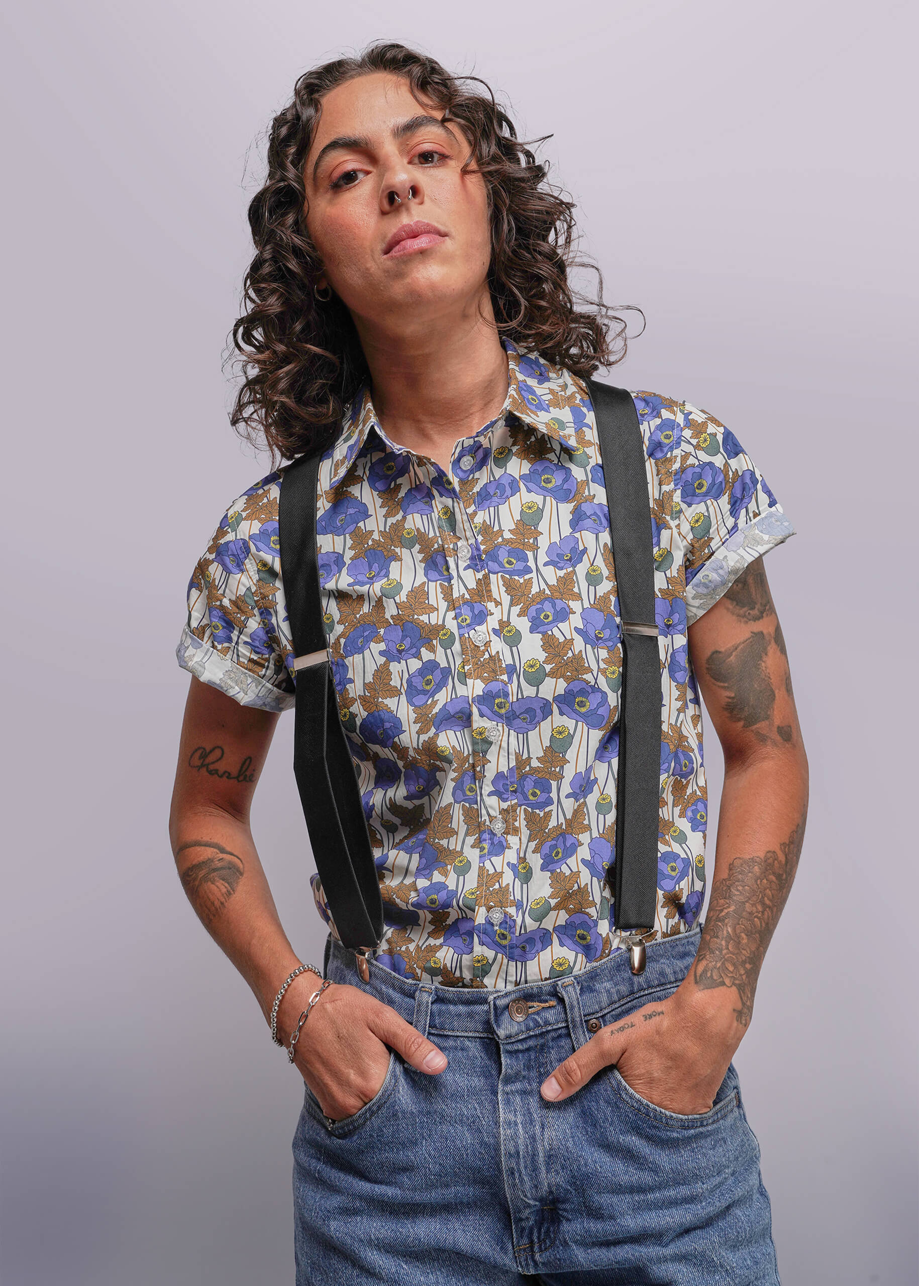S=Person wearing a floral shirt and suspenders against a plain background