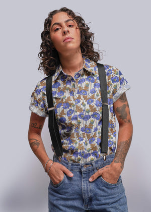 S=Person wearing a floral shirt and suspenders against a plain background