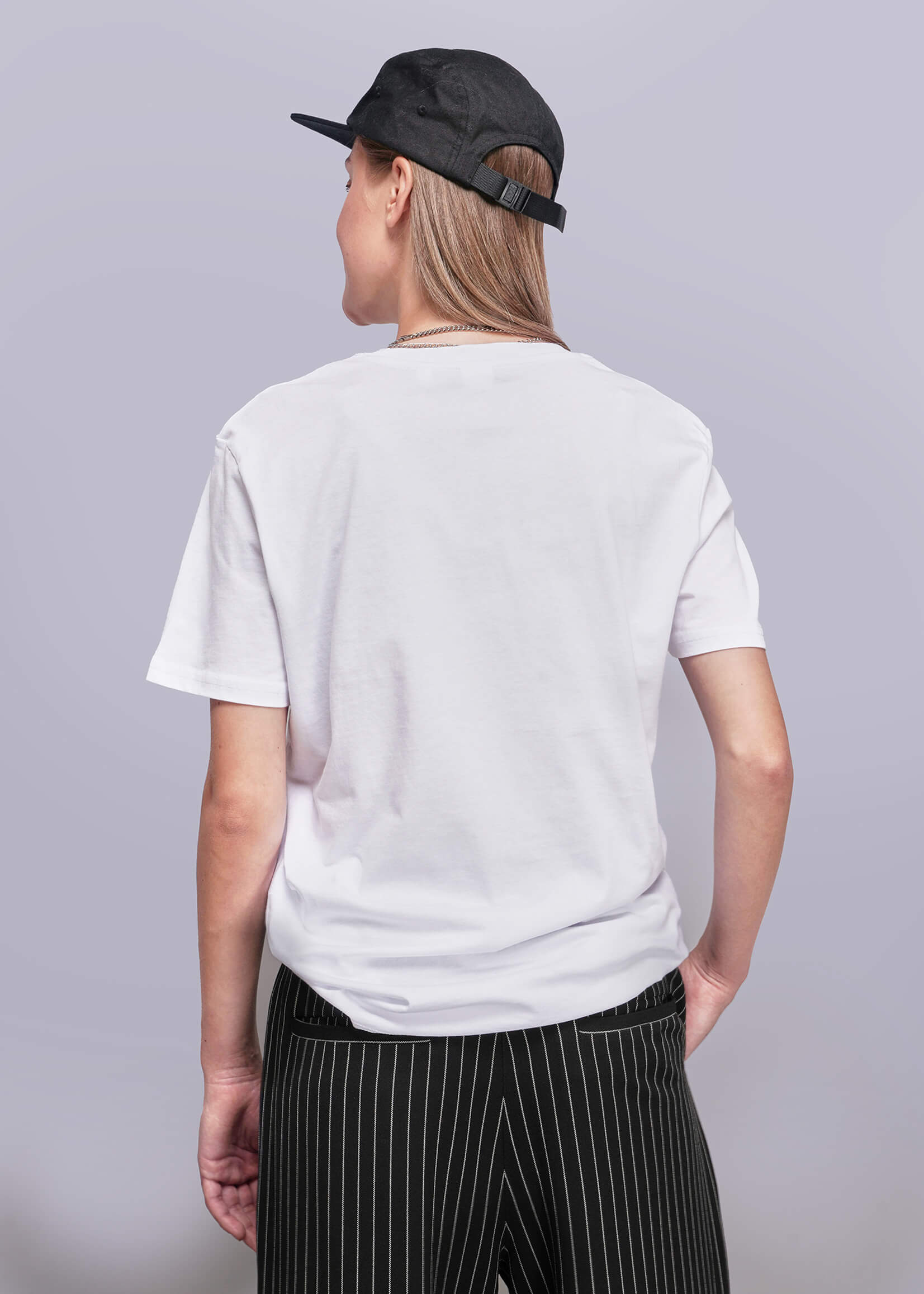 S=Person wearing a white t-shirt and black cap on a gray background