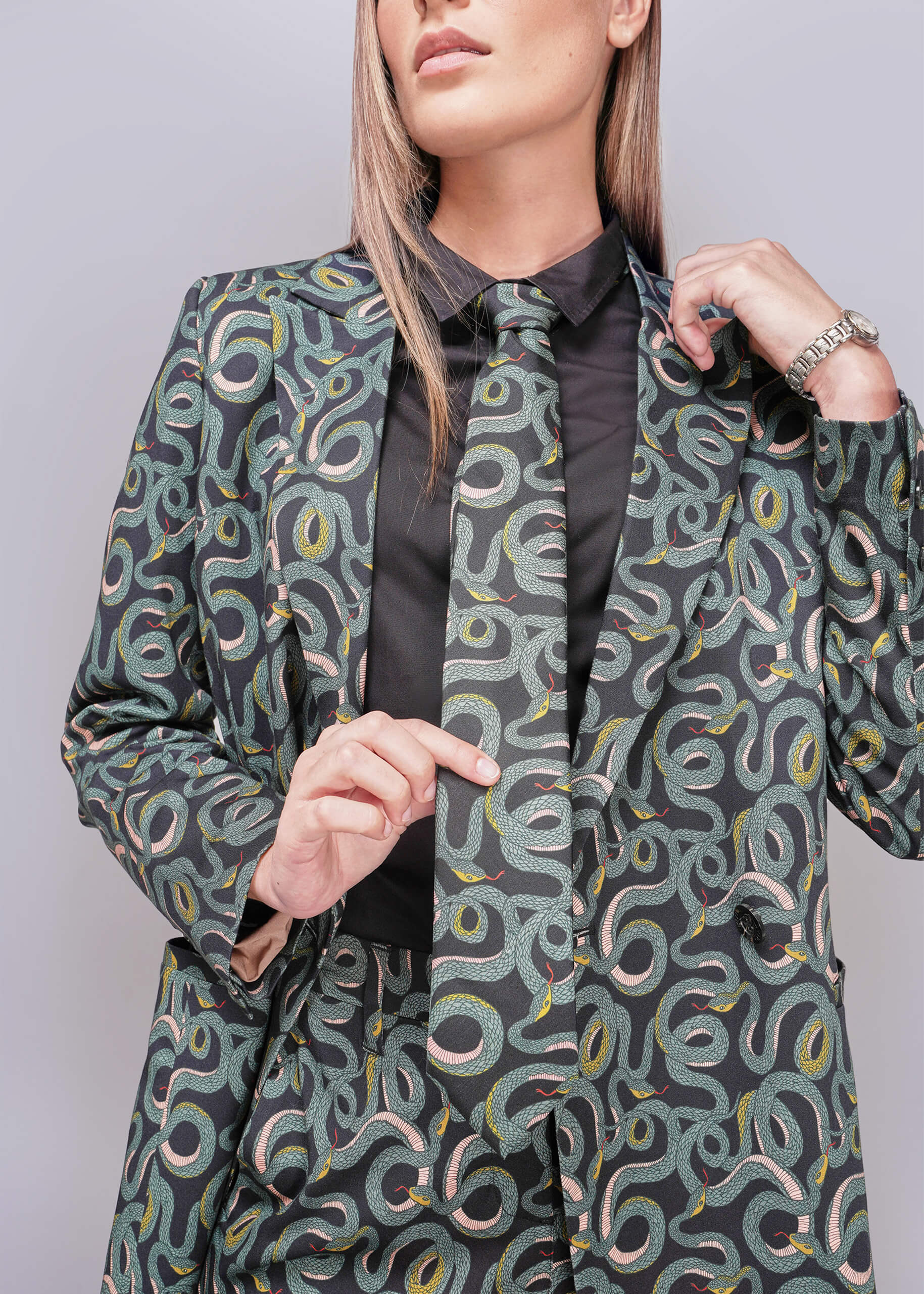 Person wearing a patterned blazer and matching tie with a plain background