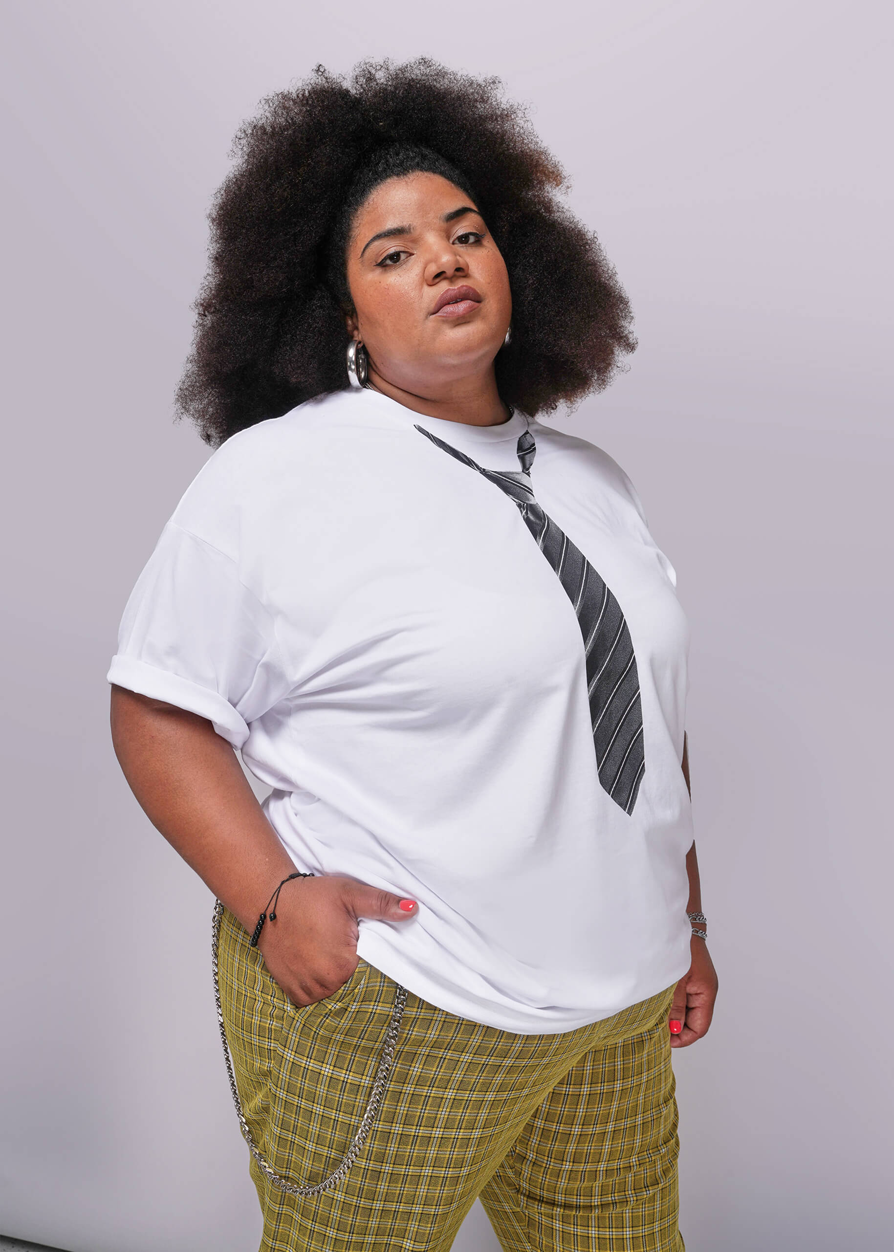 1X=Person wearing a white t-shirt with a graphic design and plaid pants on a plain background