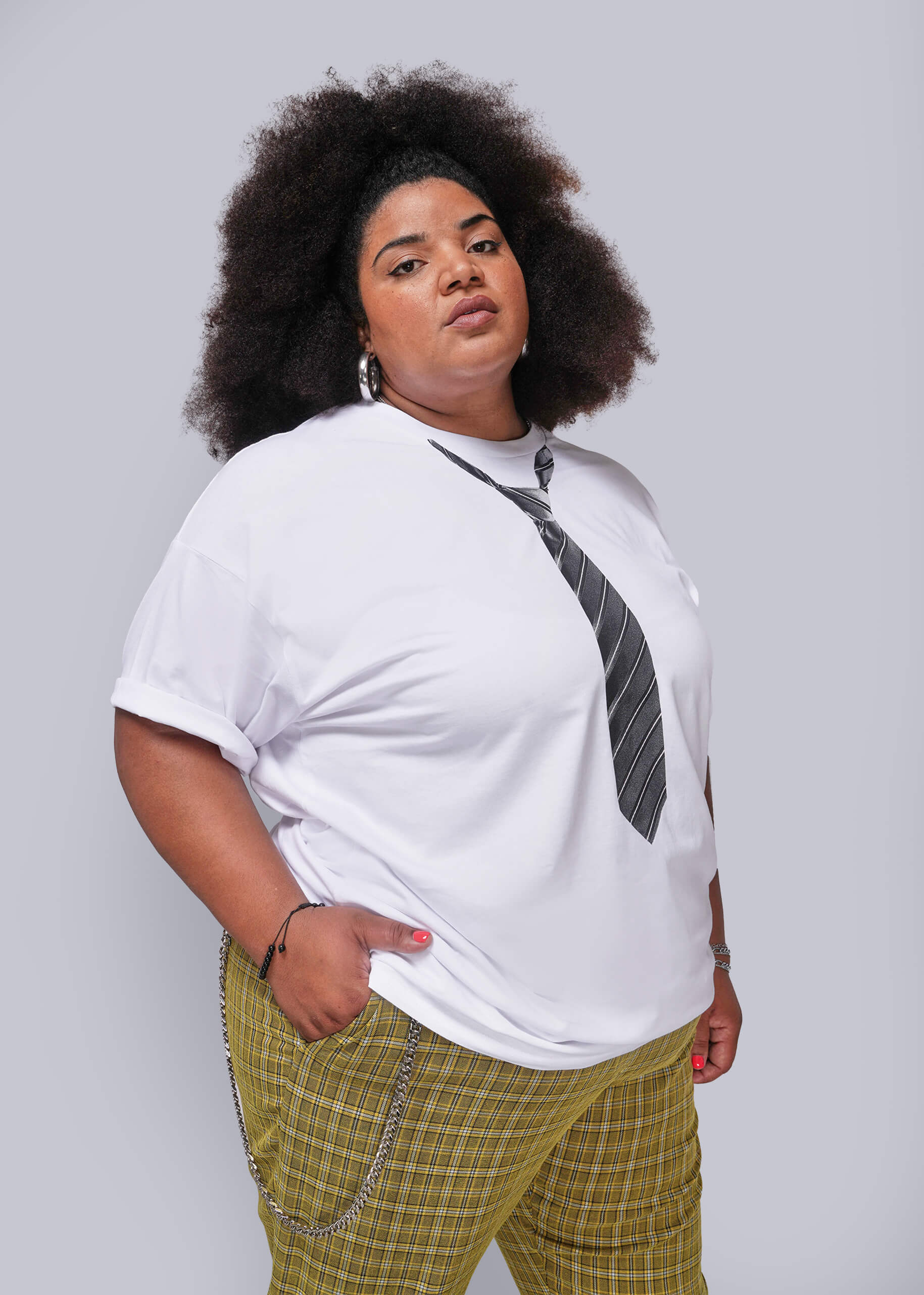 1X=Person wearing a white t-shirt with a graphic design and plaid pants on a plain background