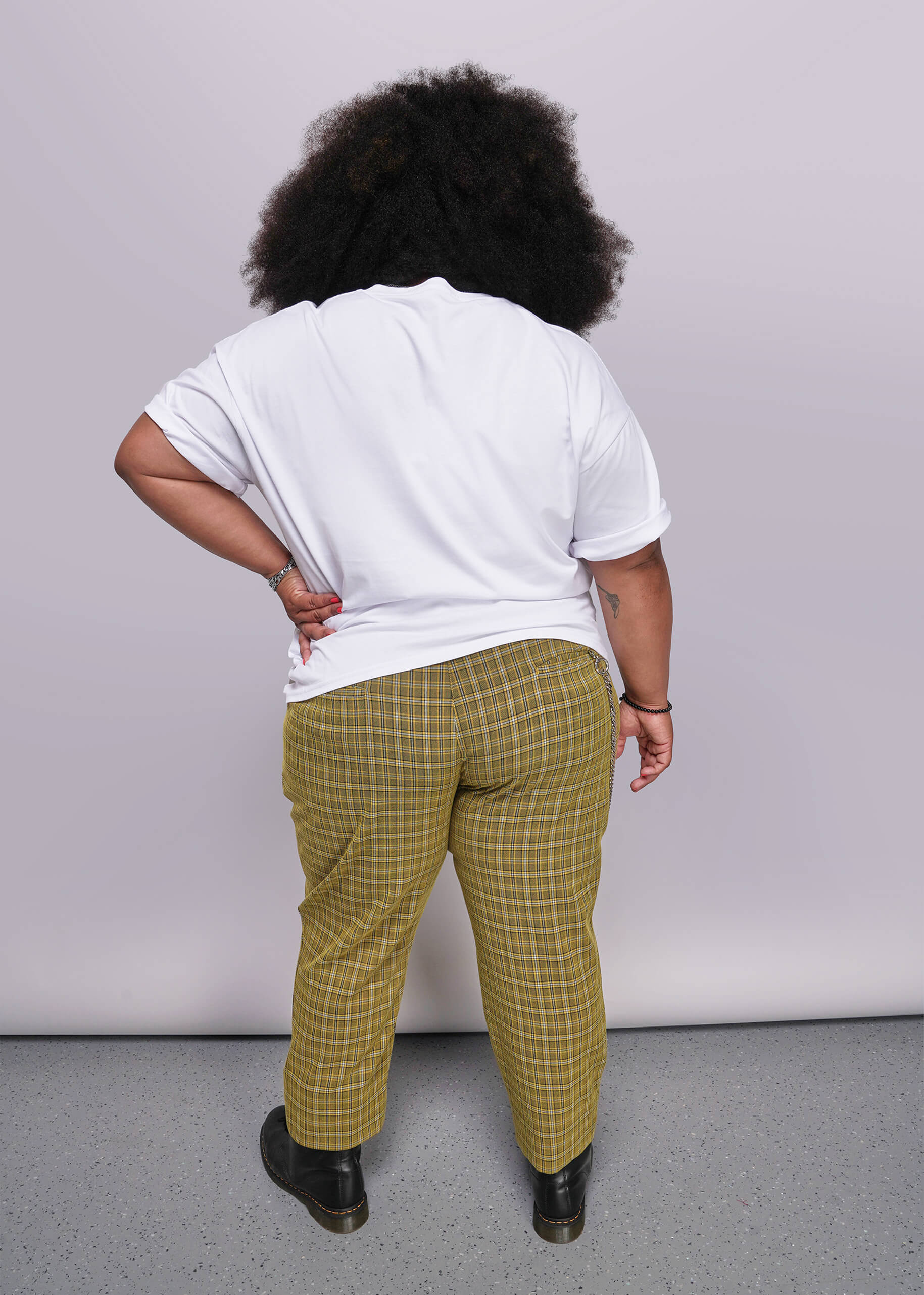 1X=Person wearing a white shirt and yellow plaid pants against a plain background