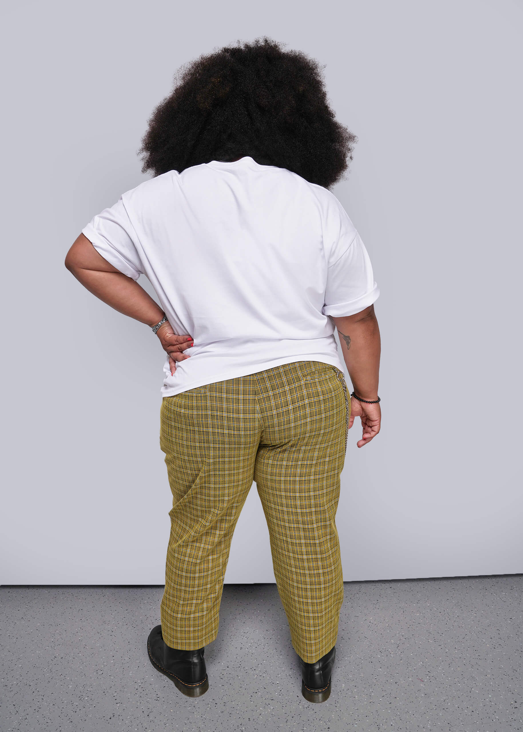 1X=Person wearing a white shirt and yellow plaid pants against a plain background
