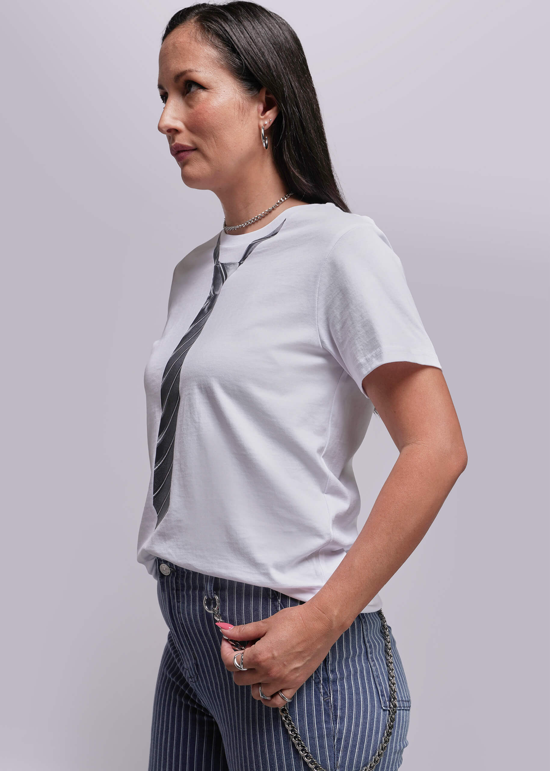 S=Woman wearing a white t-shirt with a tie design and striped pants on a plain background