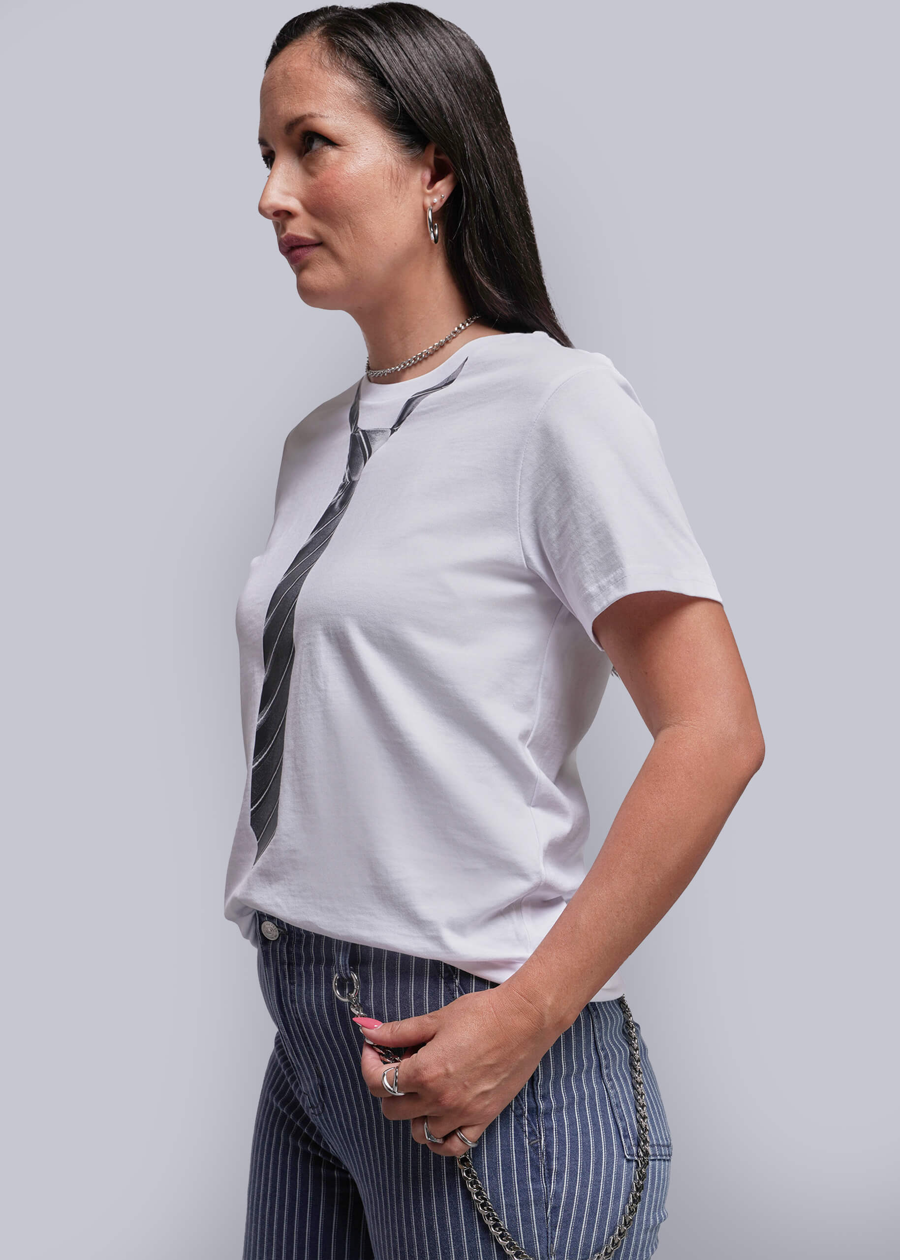 S=Woman wearing a white t-shirt with a tie design and striped pants on a plain background