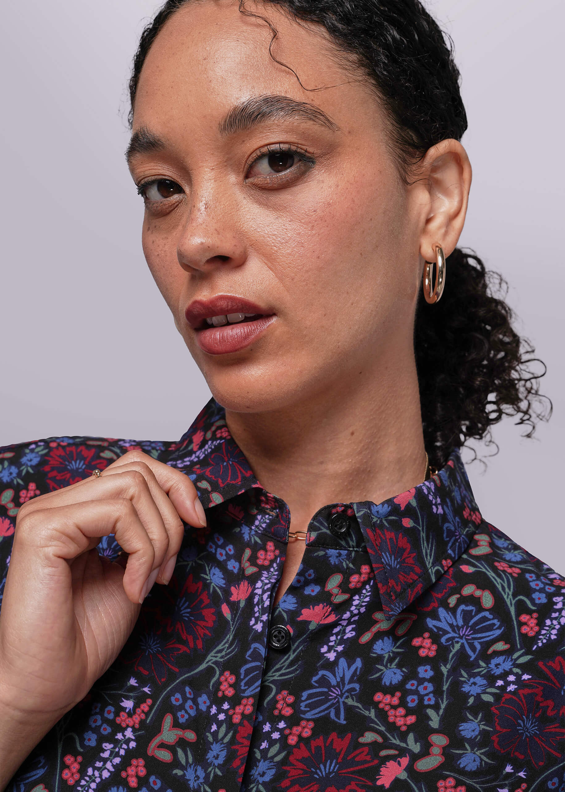 S=Close up of person wearing a floral shirt against a plain background