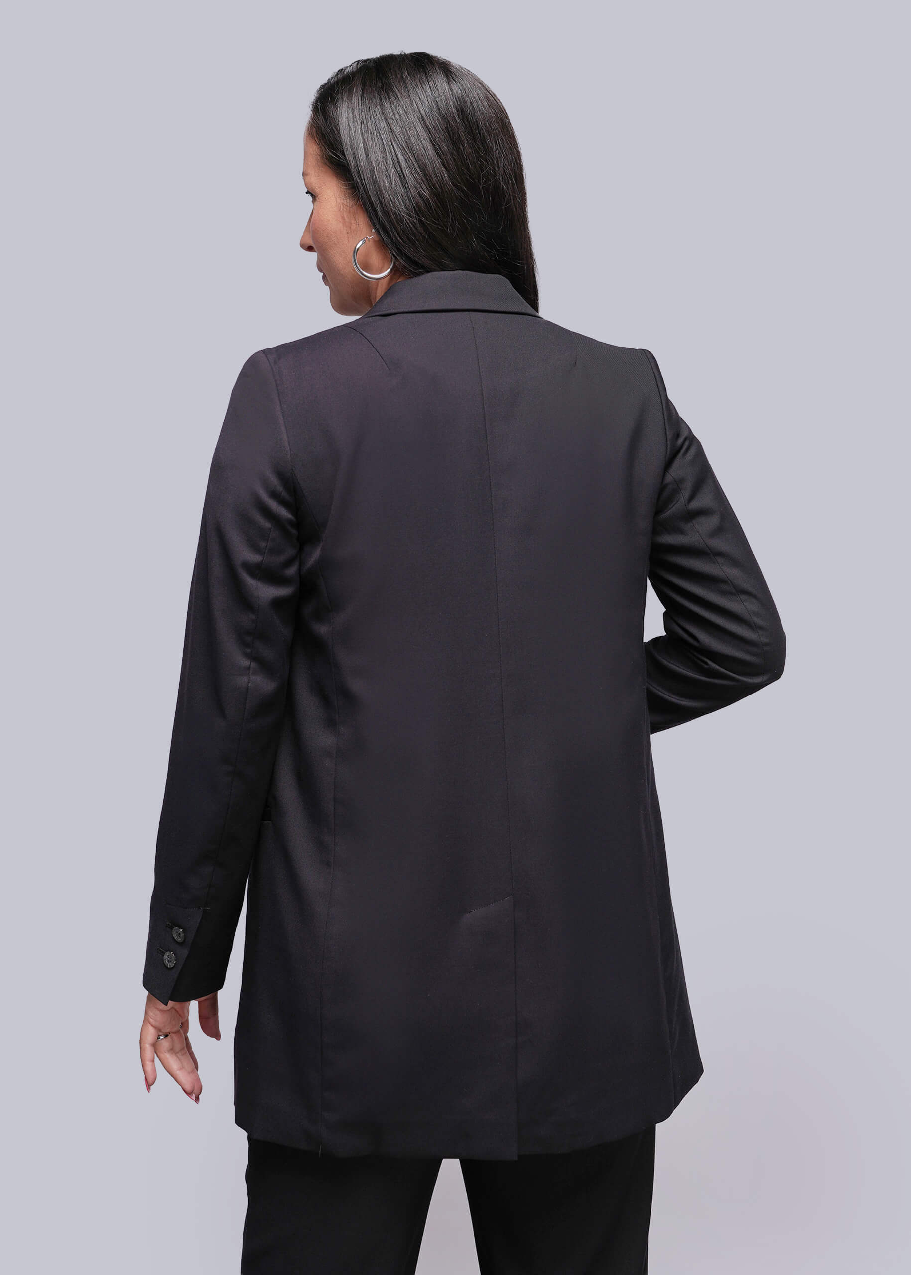 S=Person wearing a black blazer from behind on a light gray background