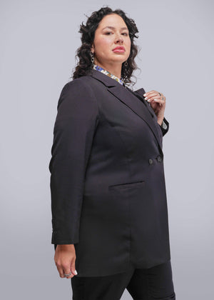 1X=Person wearing a black blazer against a plain background