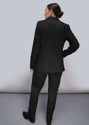 S=Back of person wearing a black suit standing against a plain background