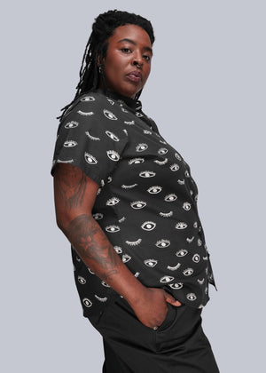 1X=Person wearing a black patterned shirt against a gray background