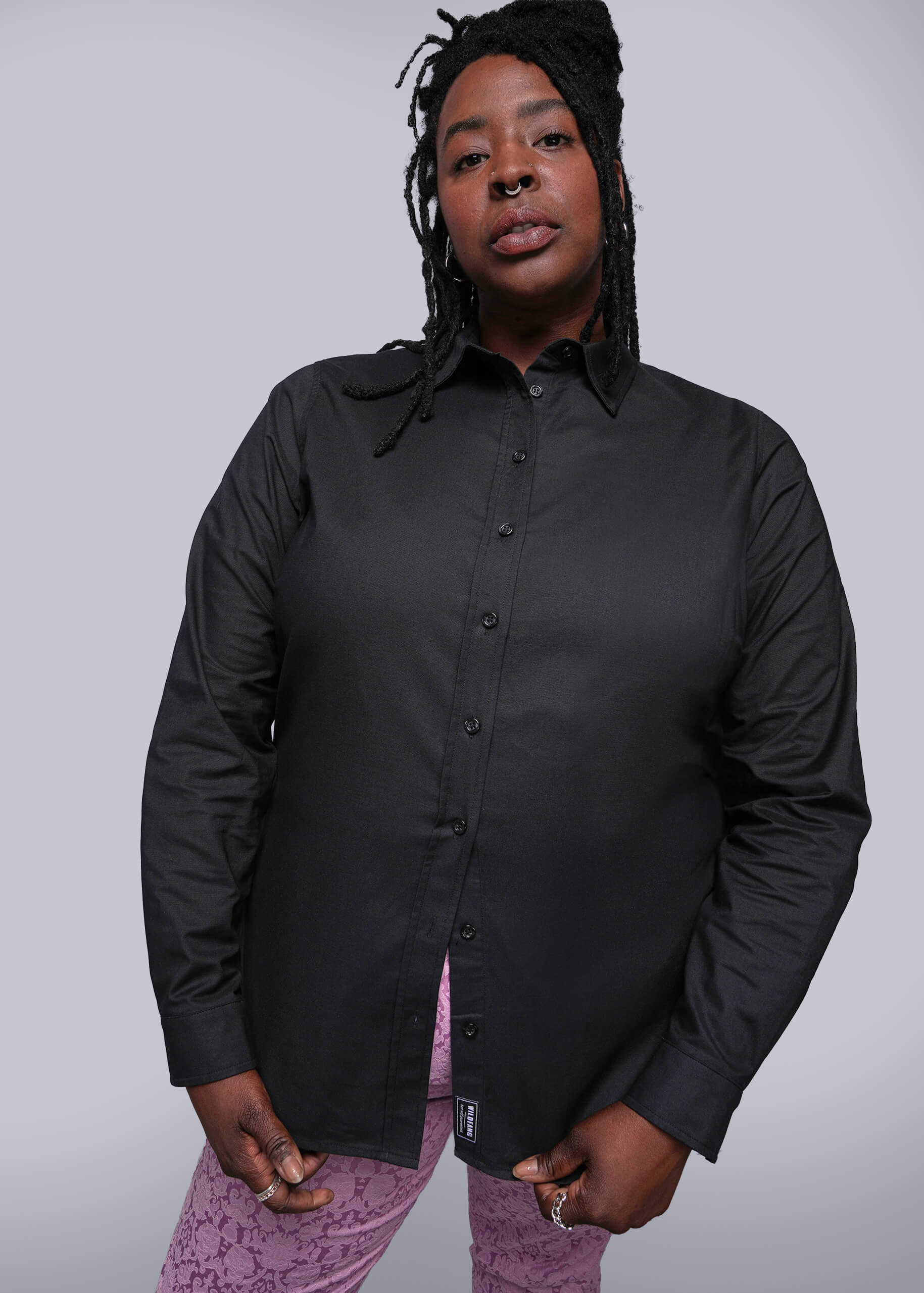 1X=Person wearing a black button-up shirt with a plain background