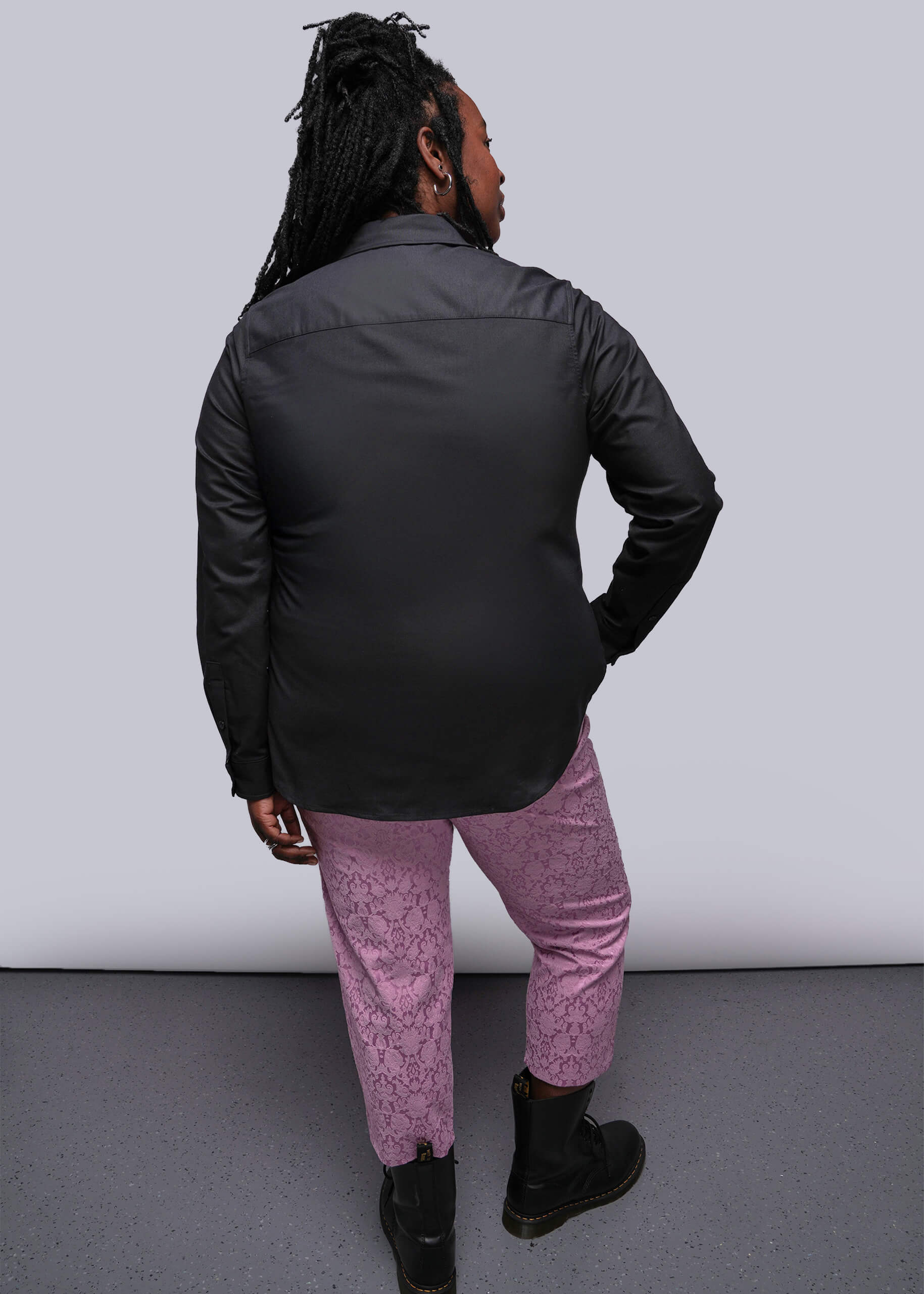 1X=Person wearing a black jacket and pink pants against a white background