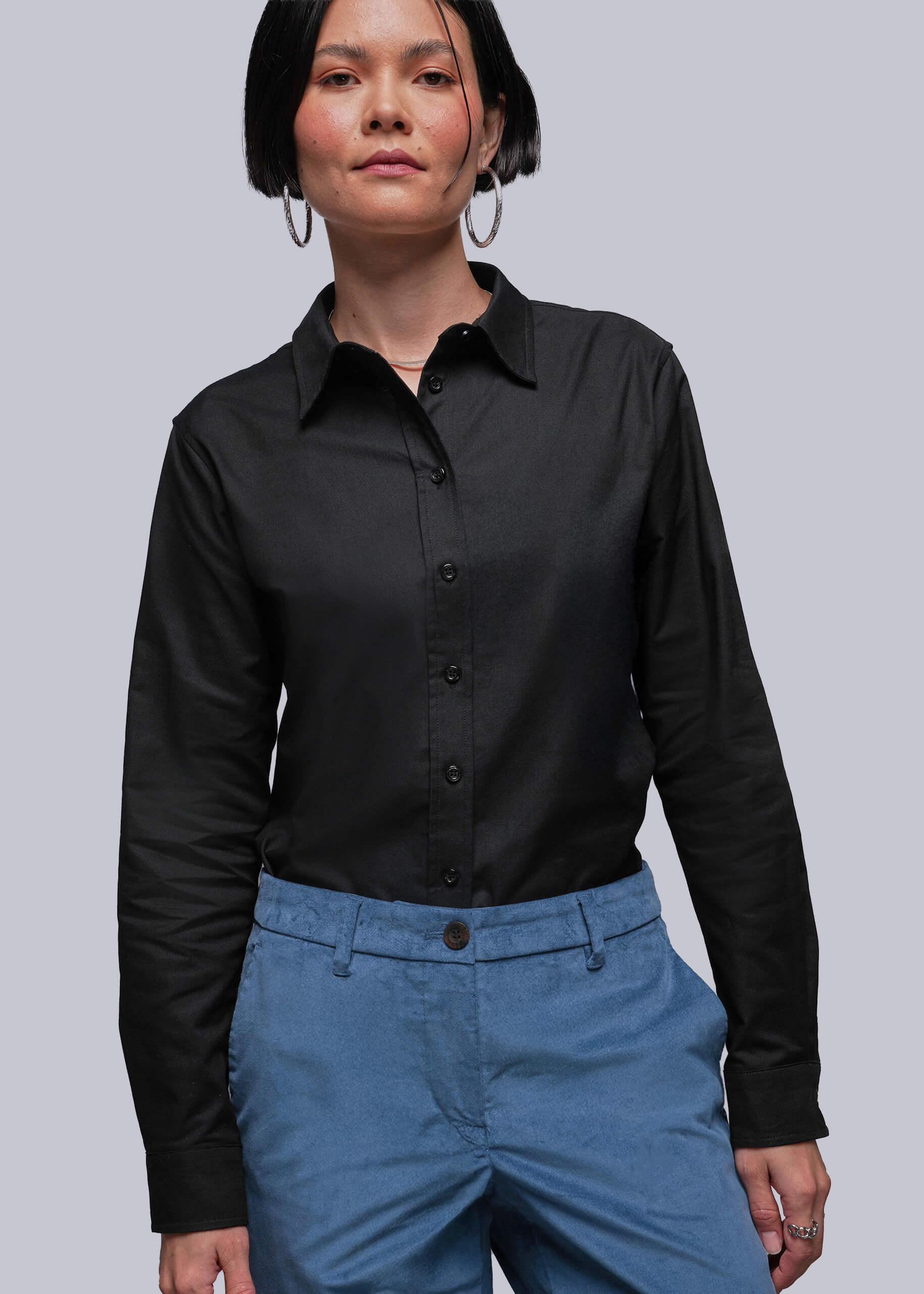 S=Person wearing a black shirt and blue pants against a plain background