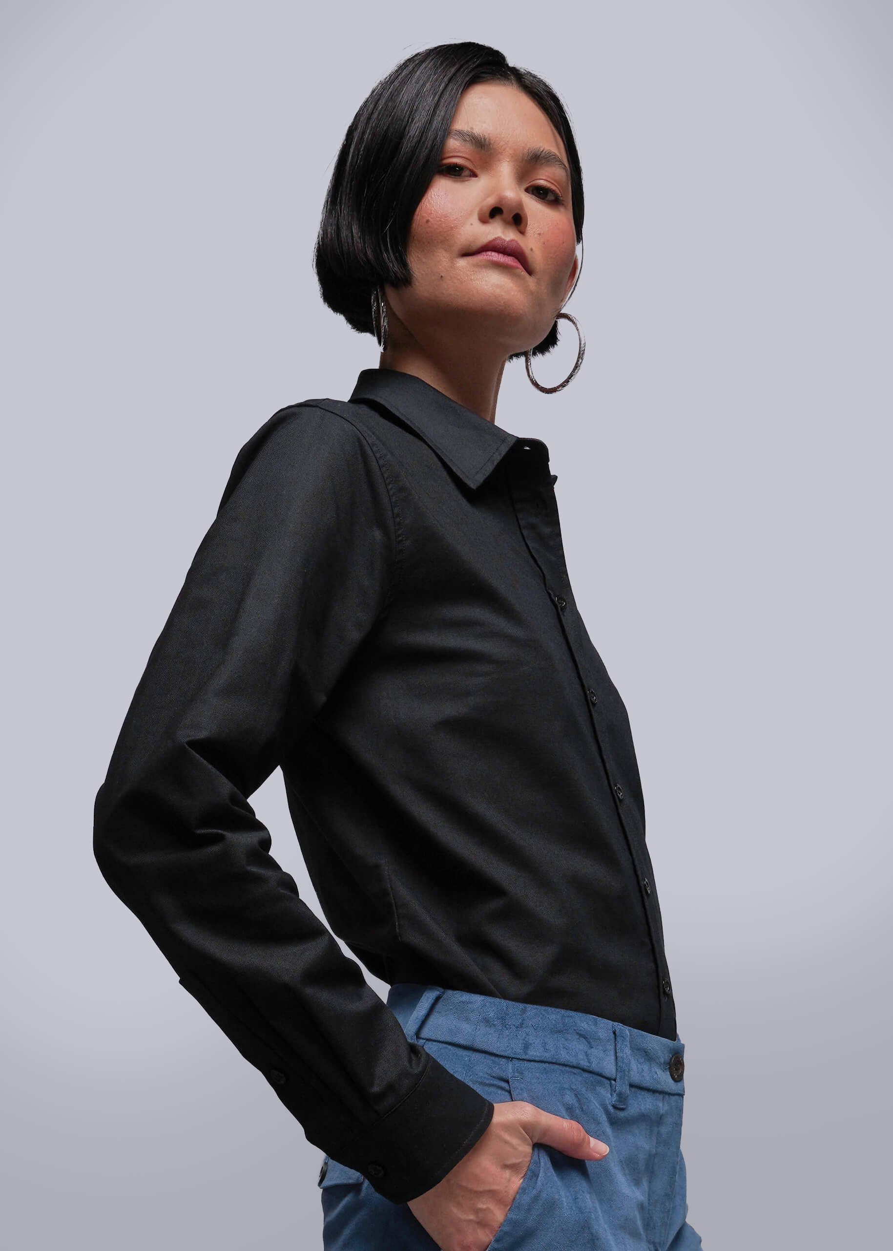 S=Person wearing a black shirt and blue pants against a gray background
