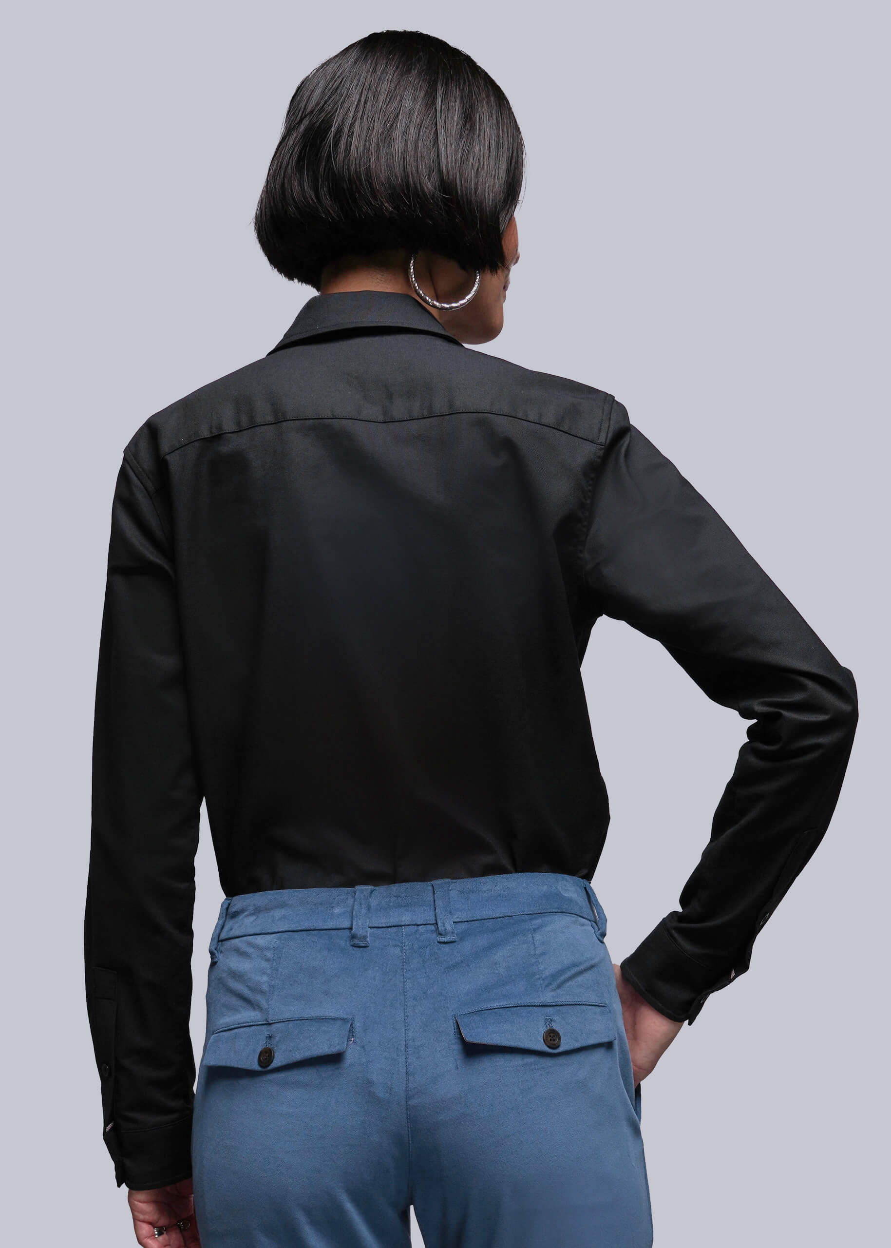 S=Person wearing a black shirt and blue pants against a gray background