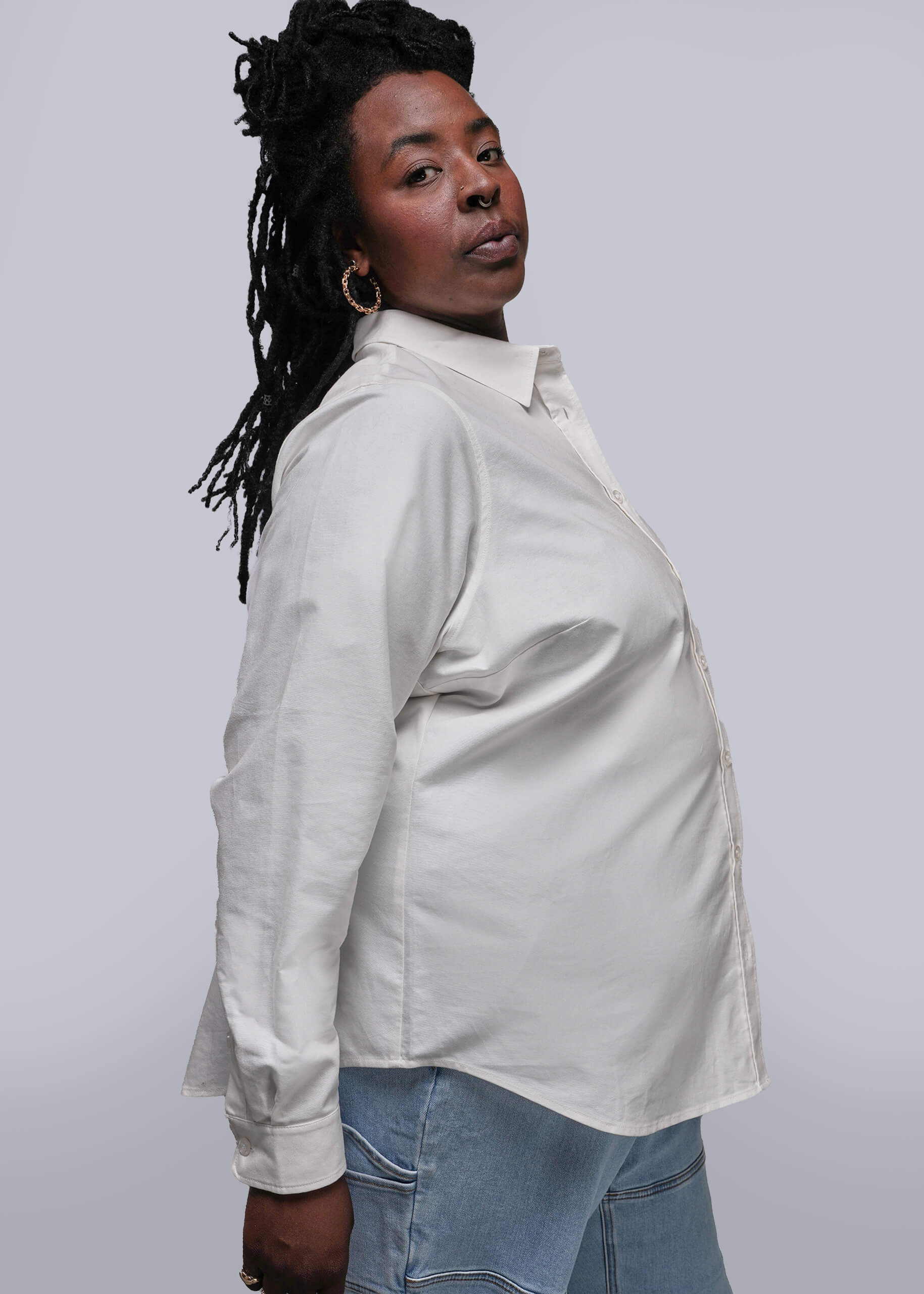 1X=Side view of Person wearing a light-colored shirt and jeans against a plain background