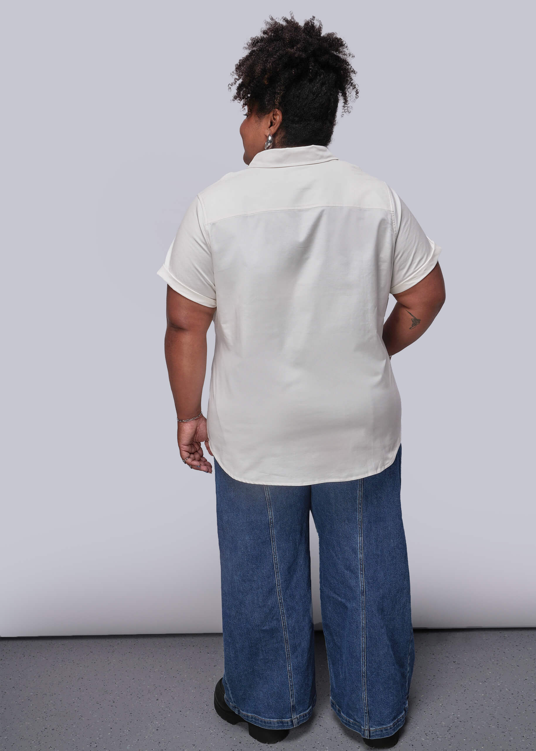 1X=Person wearing a white shirt and blue jeans against a plain background