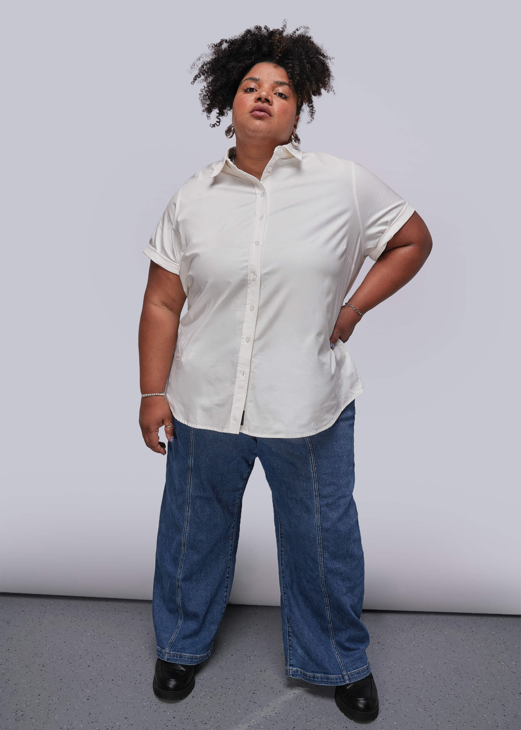 1X=Person wearing a white shirt and blue jeans against a plain background