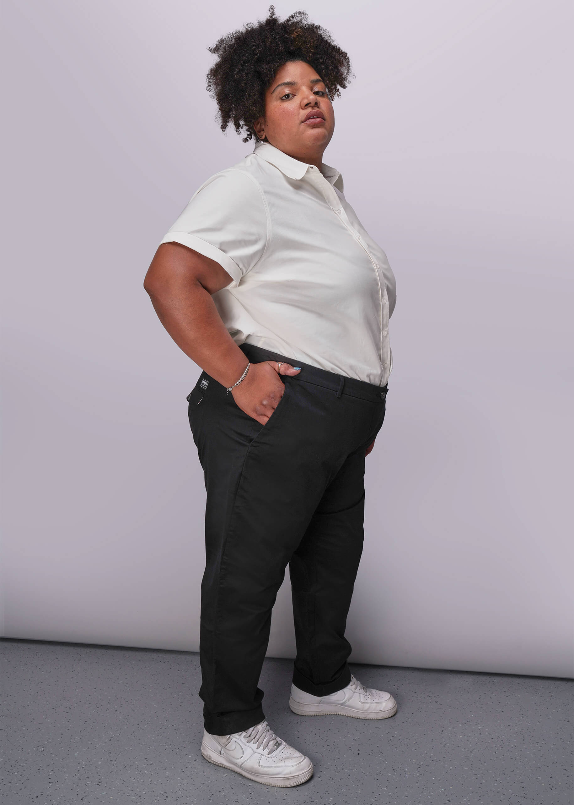 1X=Person wearing a white button up shirt and black pants against a plain background