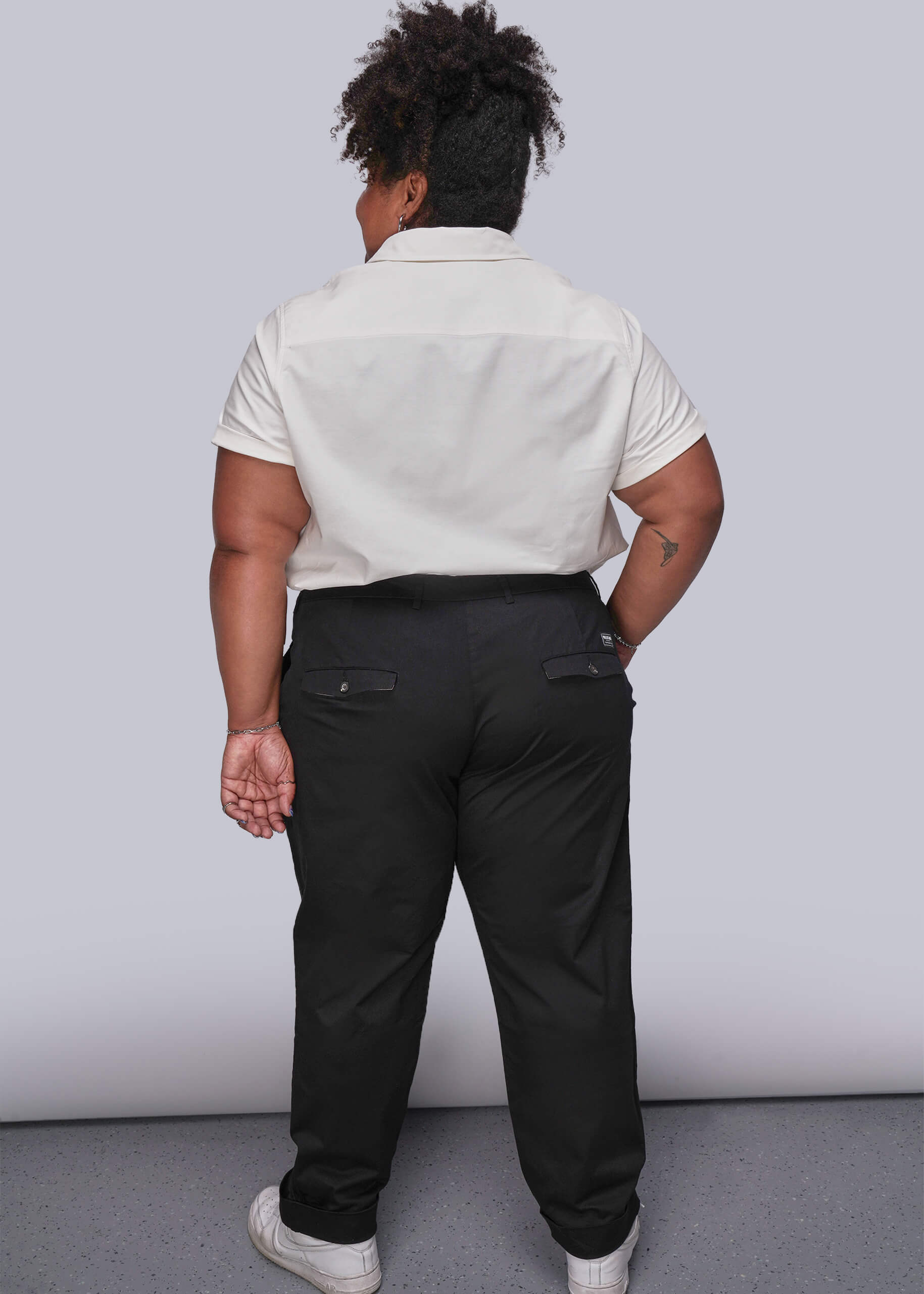 1X=Person wearing a white shirt and black pants against a plain background
