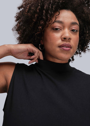1X=Person wearing a black sleeveless top against a gray background