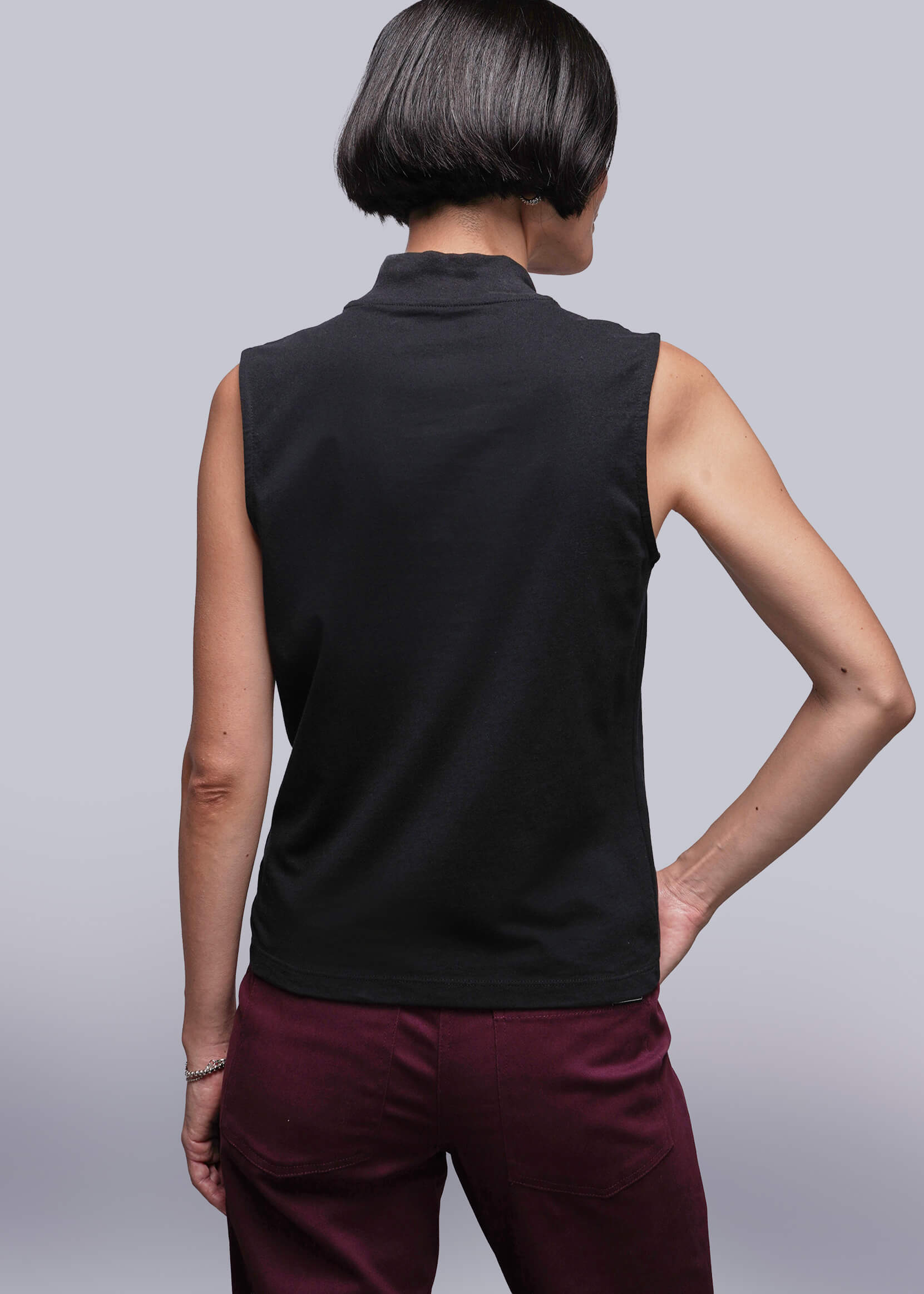 S=Person wearing a black sleeveless top and maroon pants against a light gray background