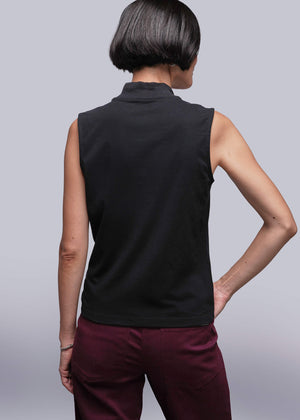 S=Person wearing a black sleeveless top and maroon pants against a light gray background