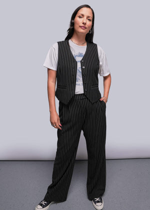 S=Model stands in front of gray background wearing pinstripe vest over t shirt and trouser