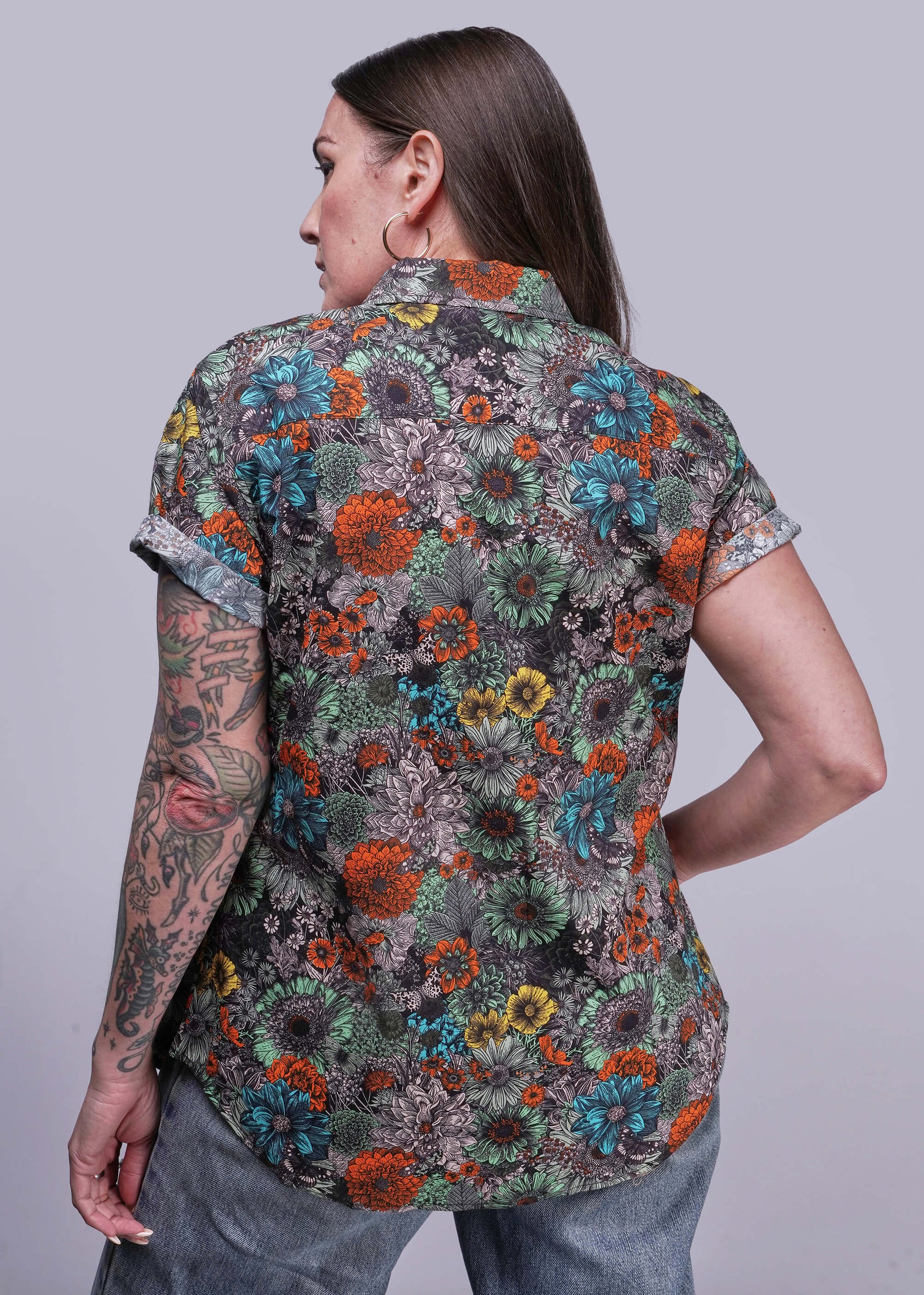 S=Person wearing a colorful floral patterned shirt on a plain background
