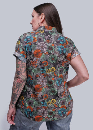 S=Person wearing a colorful floral patterned shirt on a plain background