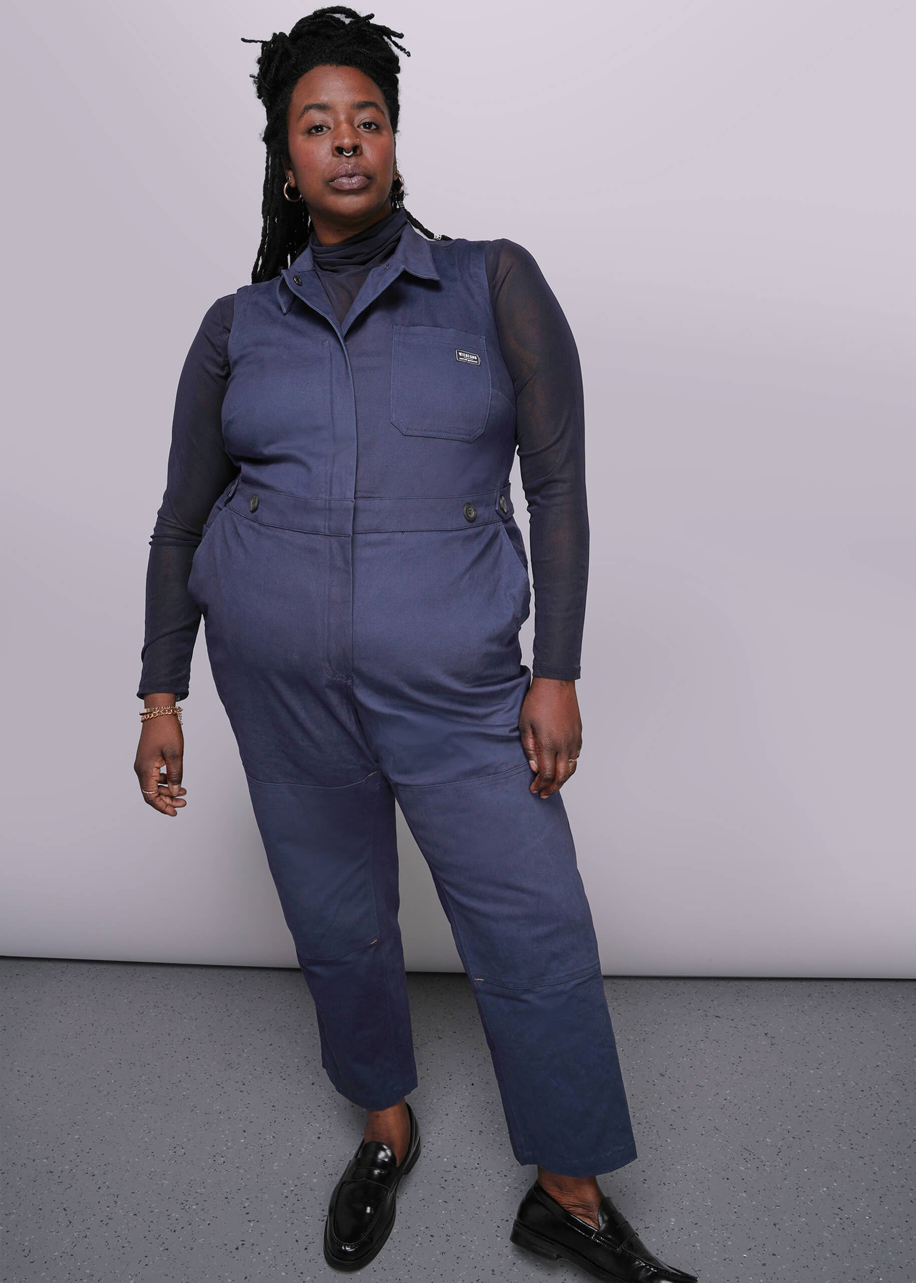1X=Person wearing a blue jumpsuit with a plain background